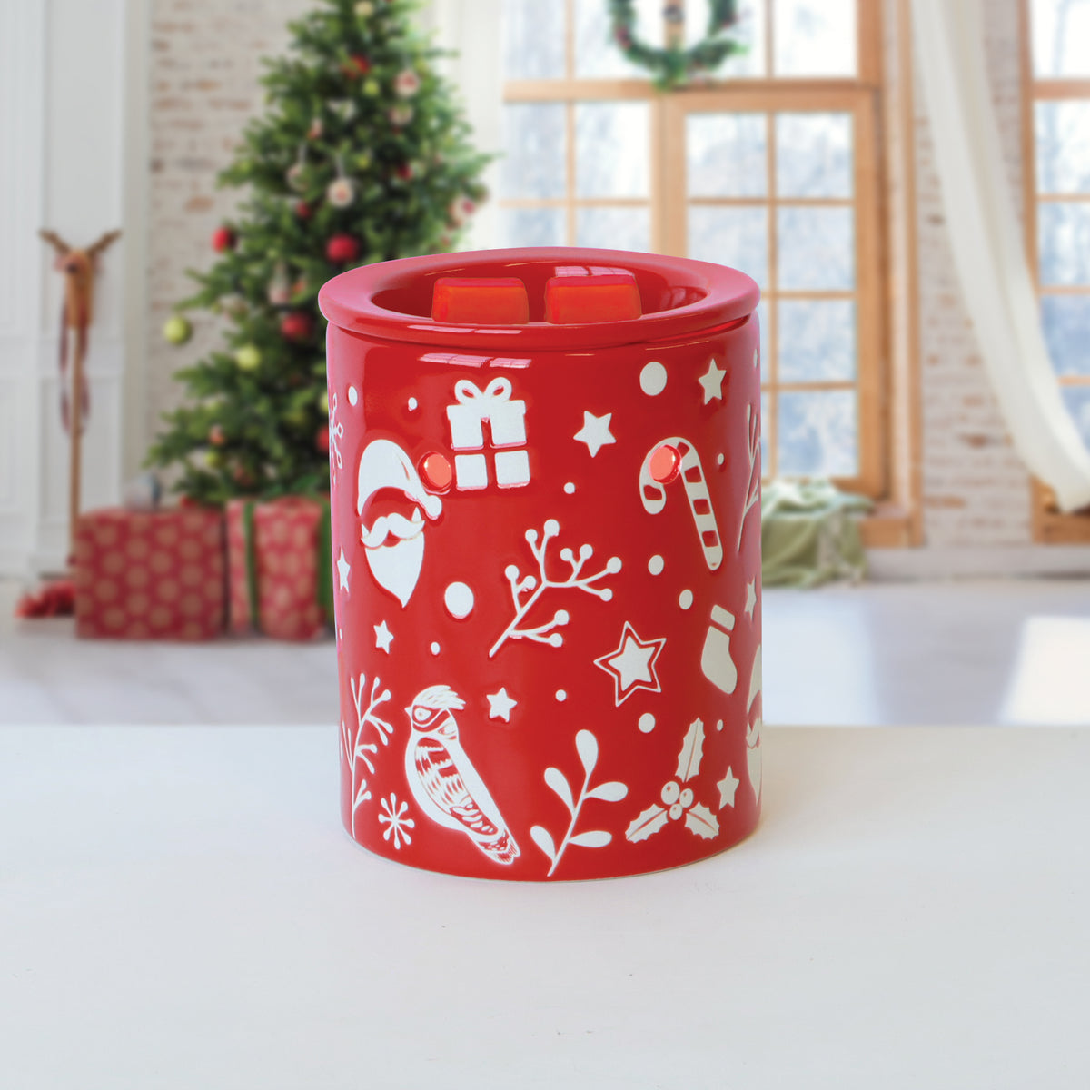 Red cylindrical Tuscany Candle® SEASONAL Warm Gingersnap: Candied Orange & Cedar Scented Holiday Wax Melt wax warmer decorated with holiday icons and two wax melts in the top dish.