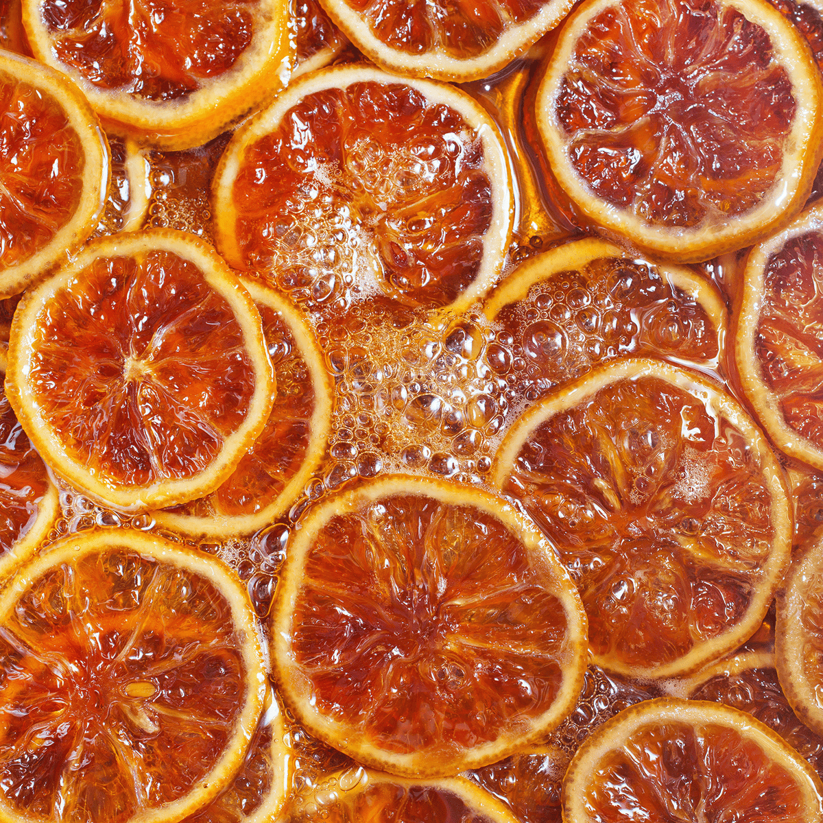 Close-up of dried orange slices submerged in melted Warm Gingersnap: Candied Orange & Cedar Scented Holiday Wax Melt (2.5 oz) with visible air bubbles.