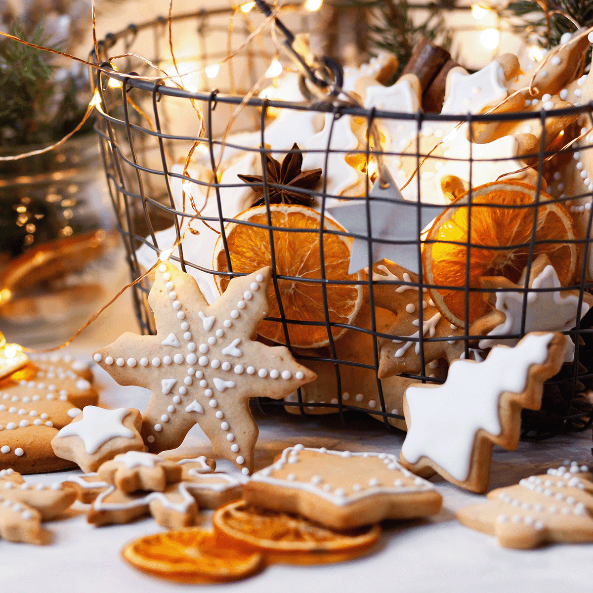 A wire basket of star-shaped sugar cookies, dried orange slices, and star anise surrounded by fairy lights, featuring a Christmas Cookies: Cinnamon Spice & Vanilla Scented Holiday Wax Melt (2.5 oz).