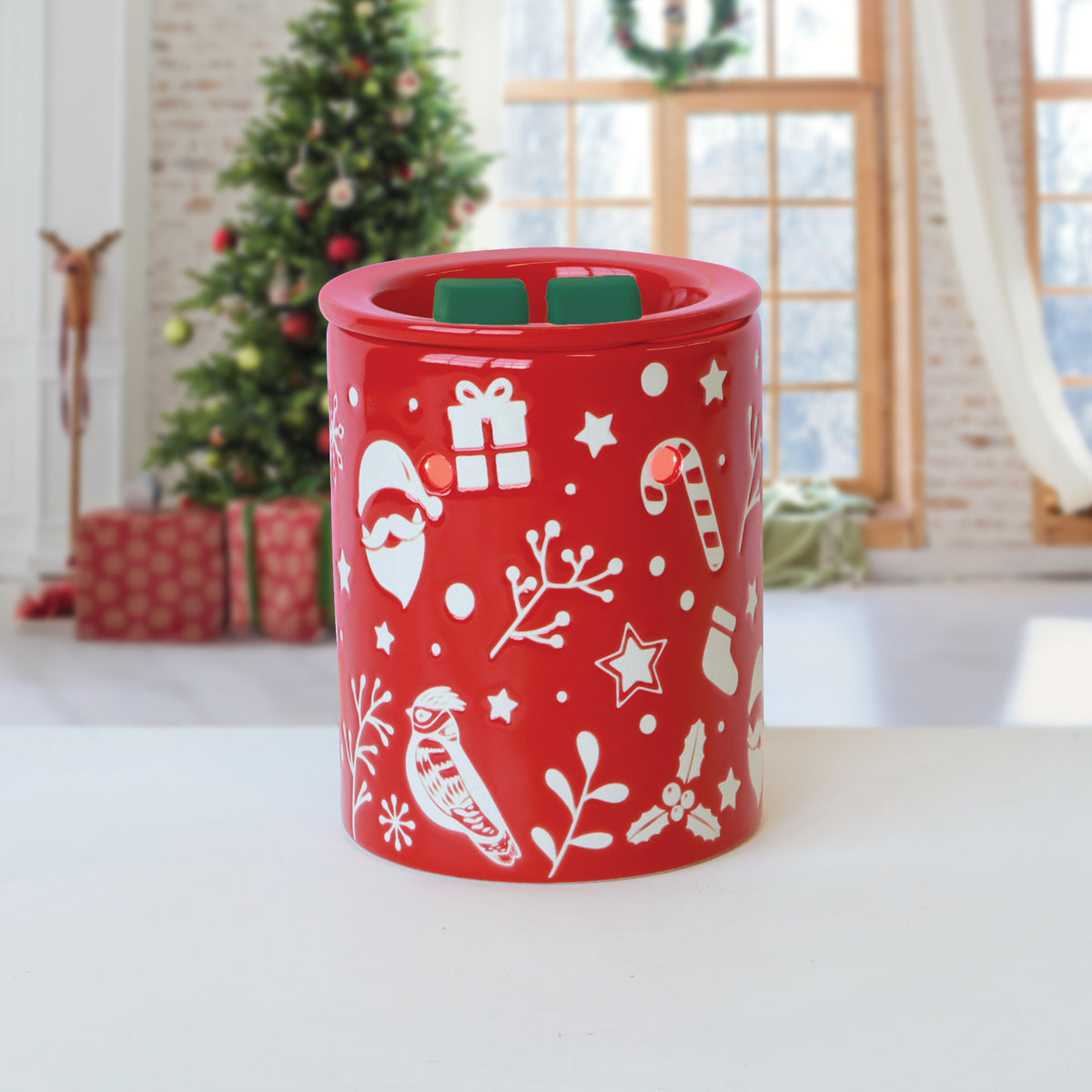 Red ceramic wax warmer decorated with white holiday icons, featuring two Woodland Path®: Evergreen & Birch Scented Holiday Wax Melt (2.5 oz) pieces on top.
