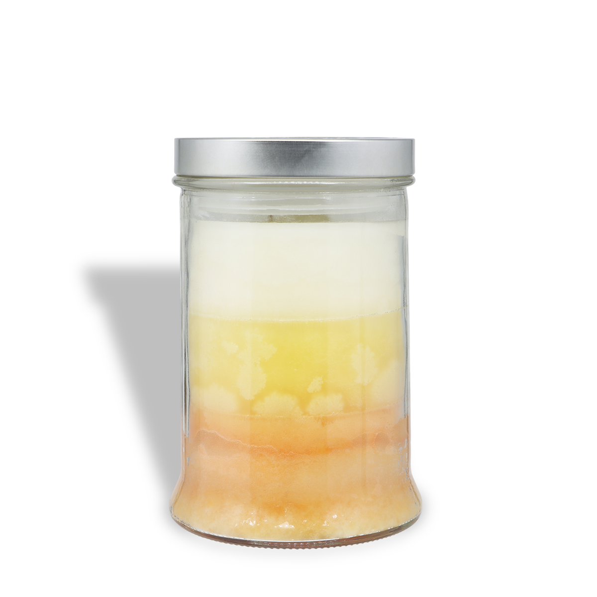 A Tuscany Candle® SEASONAL Yuletide Vanilla: Smooth Rum & Clove Scented Holiday Candle (18 oz) in a clear glass jar with three white, yellow, and orange wax layers and a silver metal lid.
