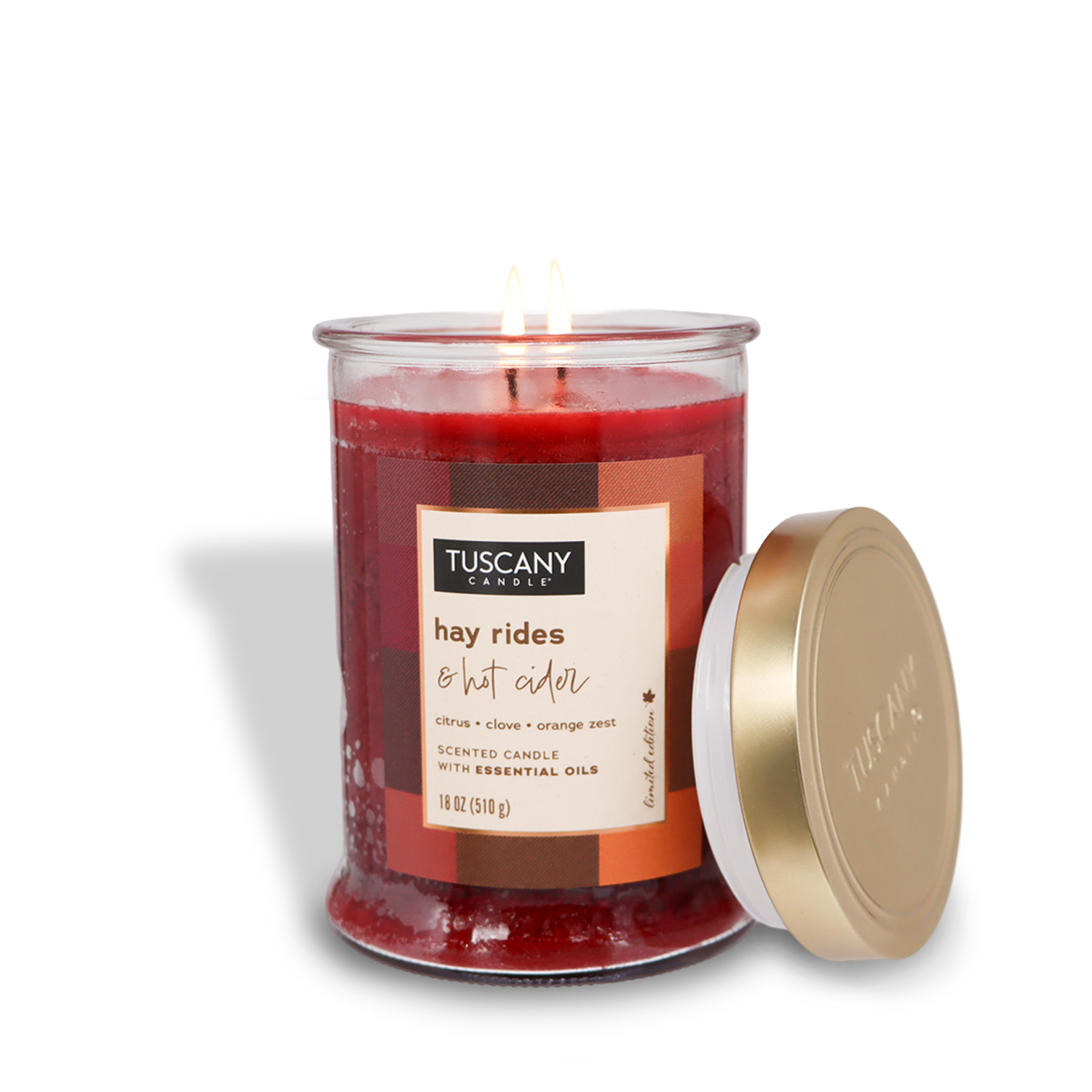 An 18 oz Tuscany Candle® SEASONAL jar candle from the Autumn Flannels Collection, named "Hay Rides & Hot Cider," with a fragrance of citrus, clove, and orange zest, sits beside its gold lid, filling the room with a cozy fall aroma.