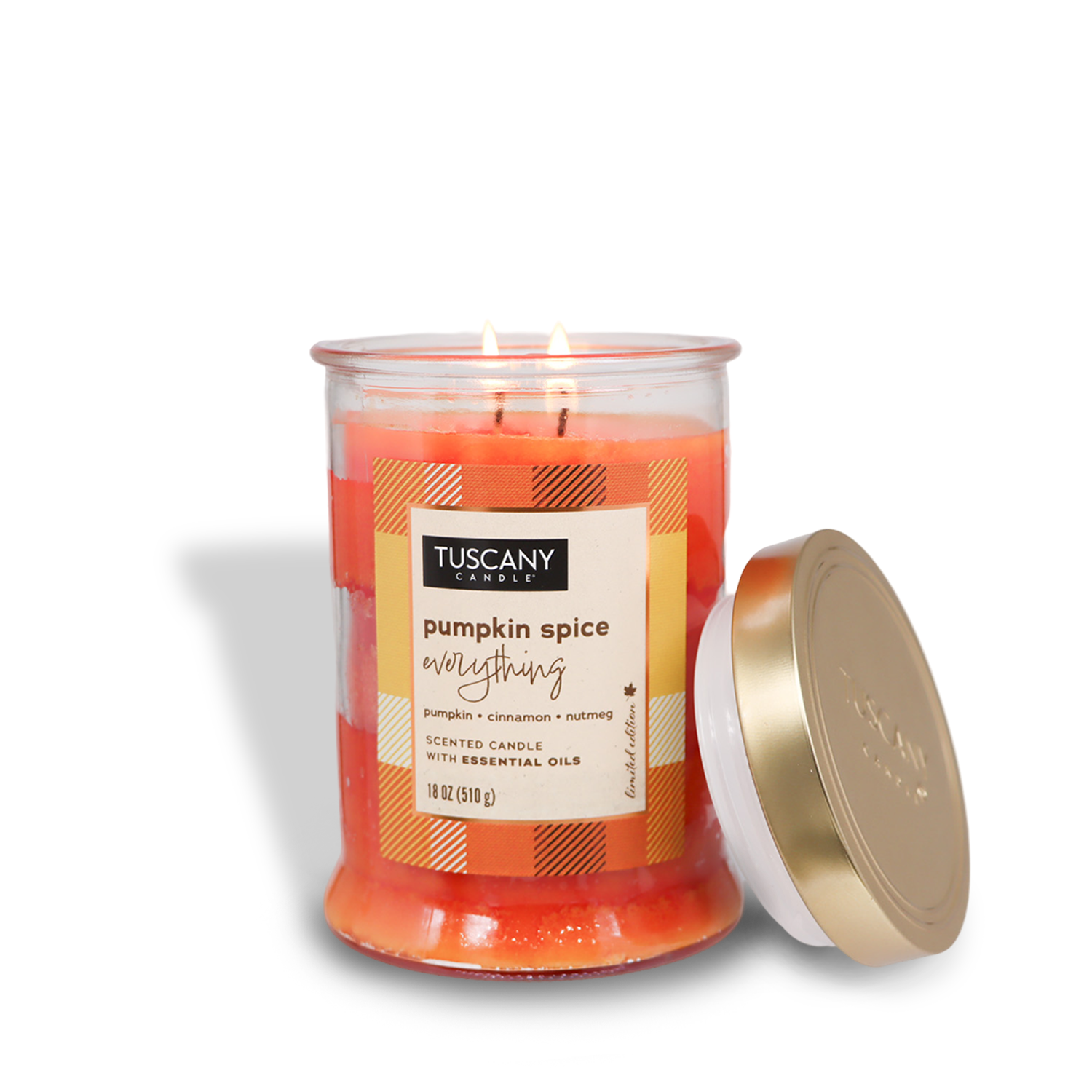 An 18 oz lit "Pumpkin Spice Everything" long-lasting scented jar candle from Tuscany Candle® SEASONAL's Autumn Flannels Collection rests in a glass jar with a gold lid beside it. The label reads, "Tuscany Candle, pumpkin spice everything, scented candle with essential oils.