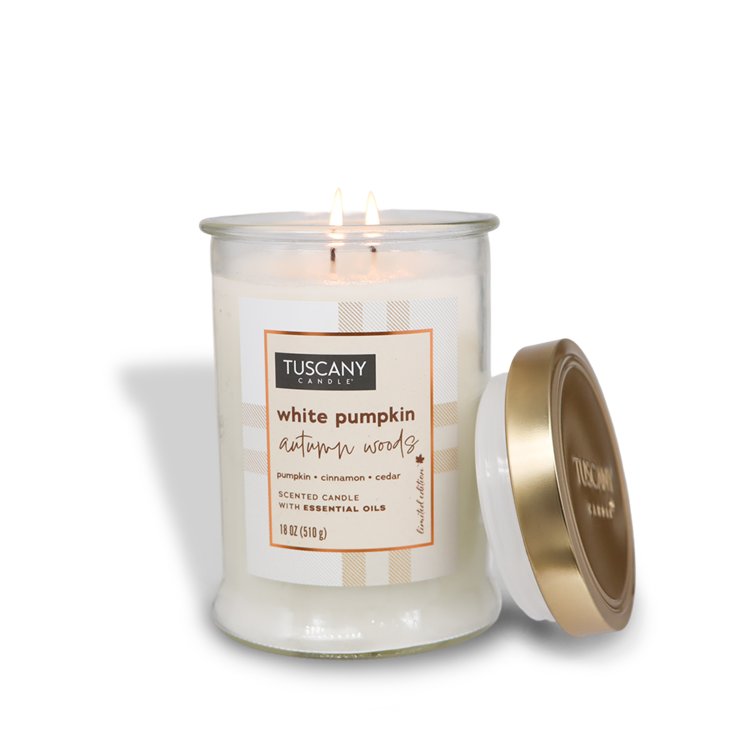 A Tuscany Candle® SEASONAL labeled "White Pumpkin Autumn Woods Long-Lasting Scented Jar Candle (18 oz)" from the Autumn Flannels Collection, with a lit double wick. The clear glass jar contains premium satin wax and has a metallic lid placed to the side. Scent notes include pumpkin, cinnamon, and cedar.