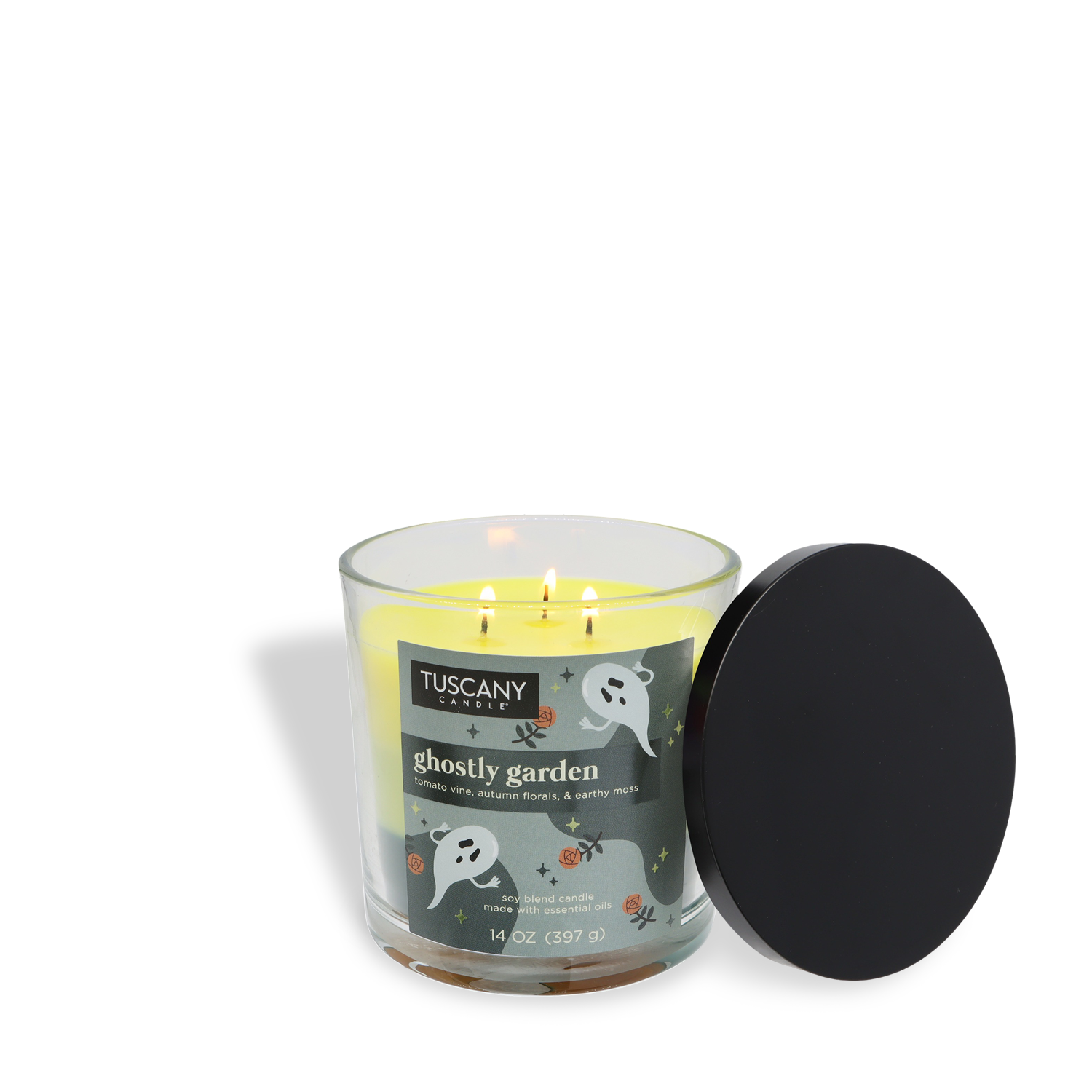 A lit Tuscany Candle® SEASONAL 14 oz "Ghostly Garden: Tomato Vine & Moss" Halloween candle, featuring ghost and spider illustrations on the glass, sits beside a black lid.