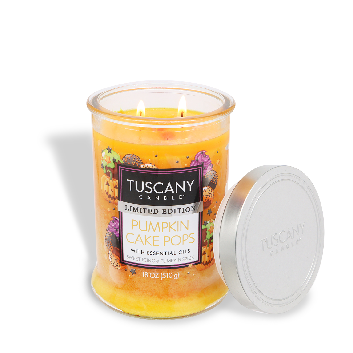 The Tuscany Candle® SEASONAL Pumpkin Cake Pops Candle (18 oz) features spice cake & vanilla icing scents, two wicks, and a glass jar with silver lid. Its label notes essential oils for a cozy autumn aroma.