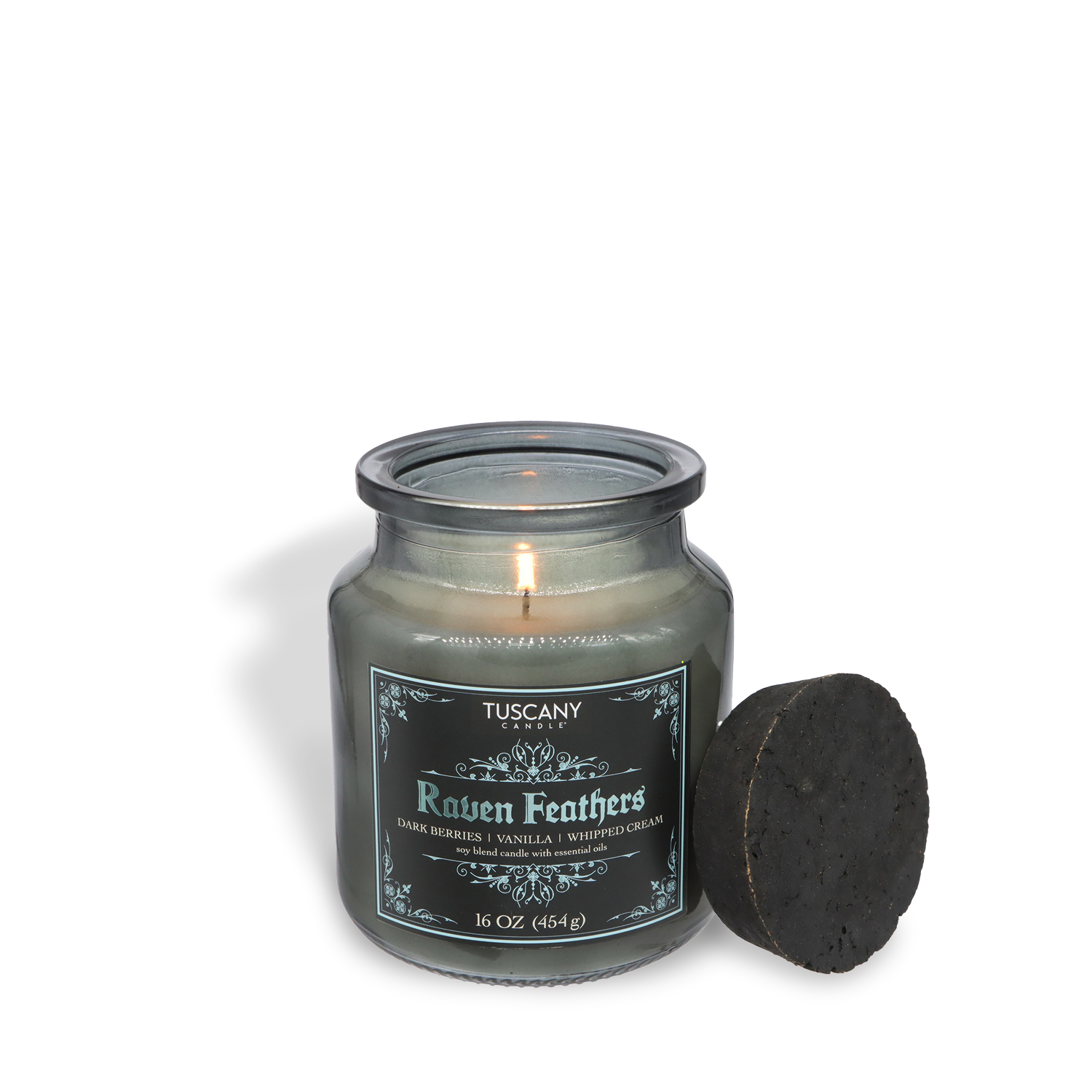 A Tuscany Candle® SEASONAL Raven Feathers: Dark Berries & Whipped Cream Scented Halloween Candle (16 oz) from the Apothecary Collection fills the room with long-lasting fragrance, its lid resting beside the glass jar.