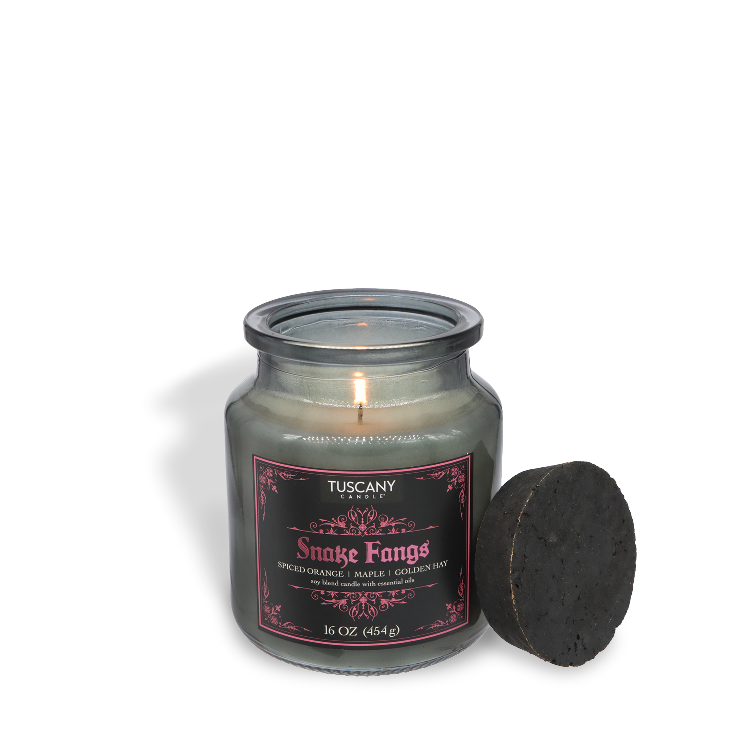 A lit Tuscany Candle® SEASONAL "Snake Fangs: Spiced Orange & Golden Hay" 16 oz Halloween candle in a glass jar with black lid, label notes of spiced orange, maple, and golden honey from the Apothecary Collection.