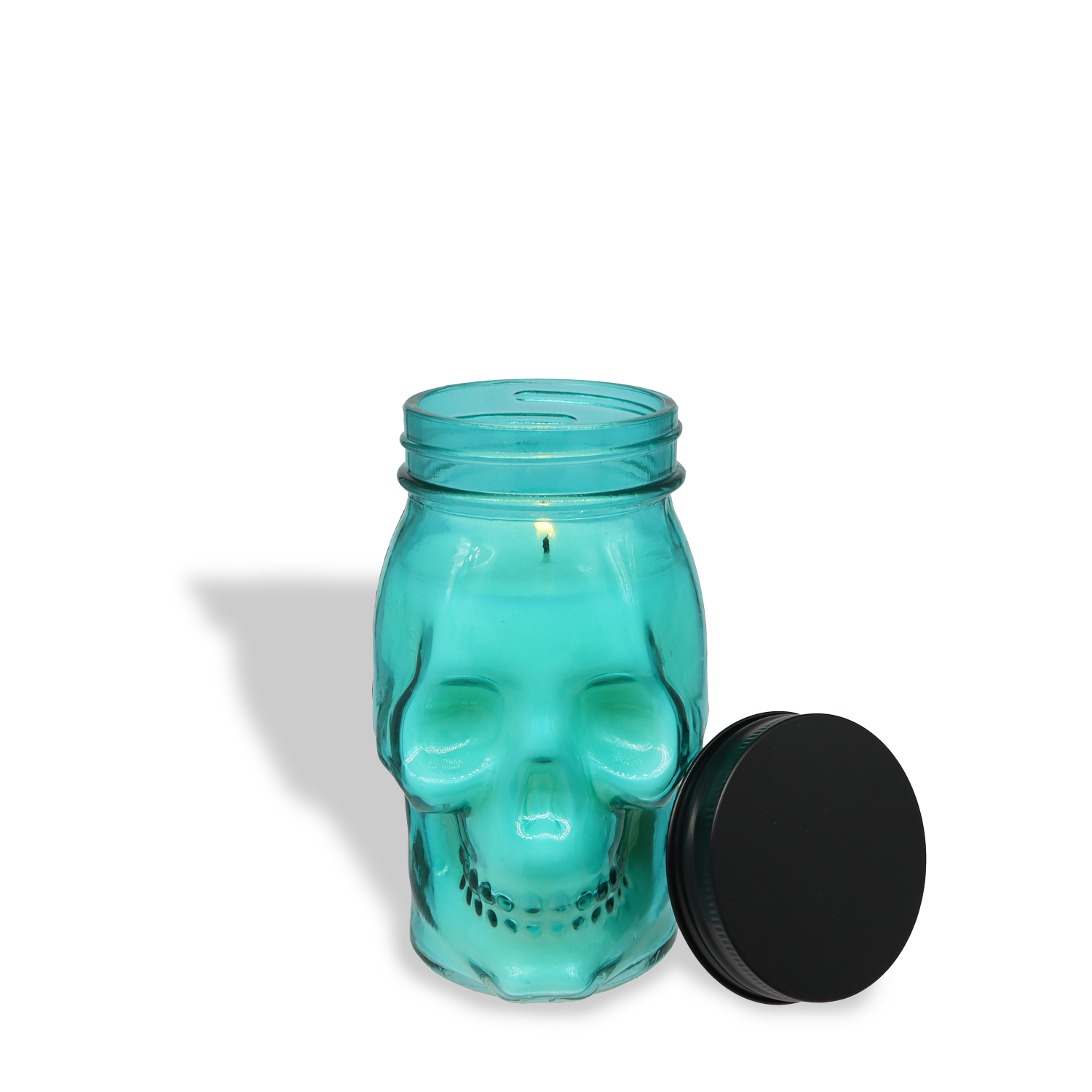 The Tuscany Candle® SEASONAL Twilight Oud: Dark Patchouli & Rich Oud Scented Halloween Candle (12 oz) from the Spooky Skull Collection features a turquoise skull jar with a lit wick and black lid, perfect for gothic décor on any white surface.