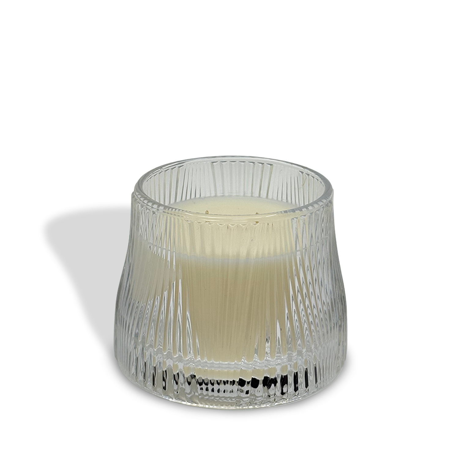 The est.1951 Linen & Pomelo Grove (9oz) luxury candle, crafted with vegan wax, rests in a textured transparent glass holder on a white surface, casting a faint shadow to the left.