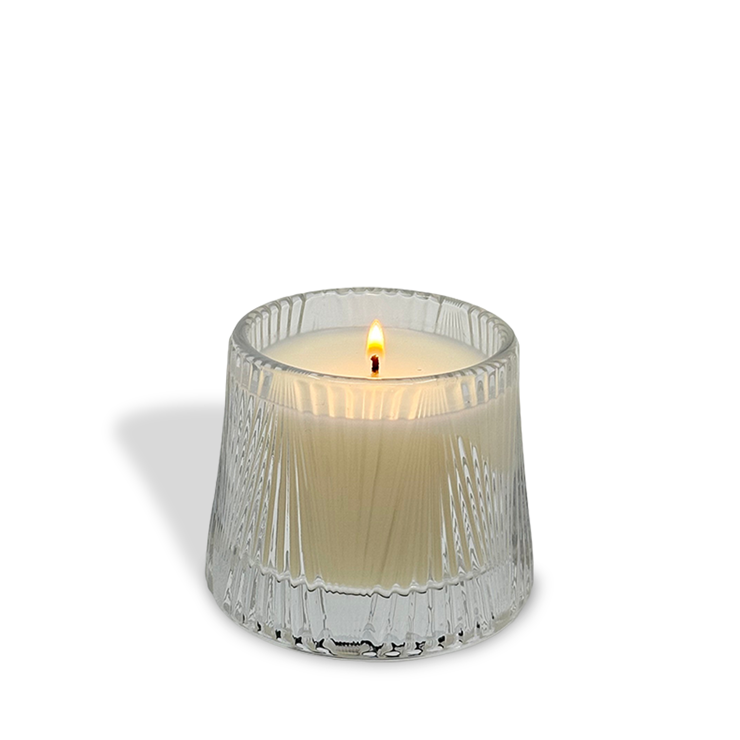 A lit est.1951 Linen & Pomelo Grove (4oz) candle in a textured transparent glass holder fills the air with a refreshing coastal scent against a plain white background.