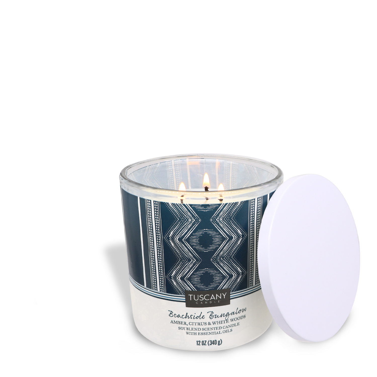 Lit Beachside Bungalow scented candle with a white lid on the side against a white background. (Tuscany Candle® SEASONAL)