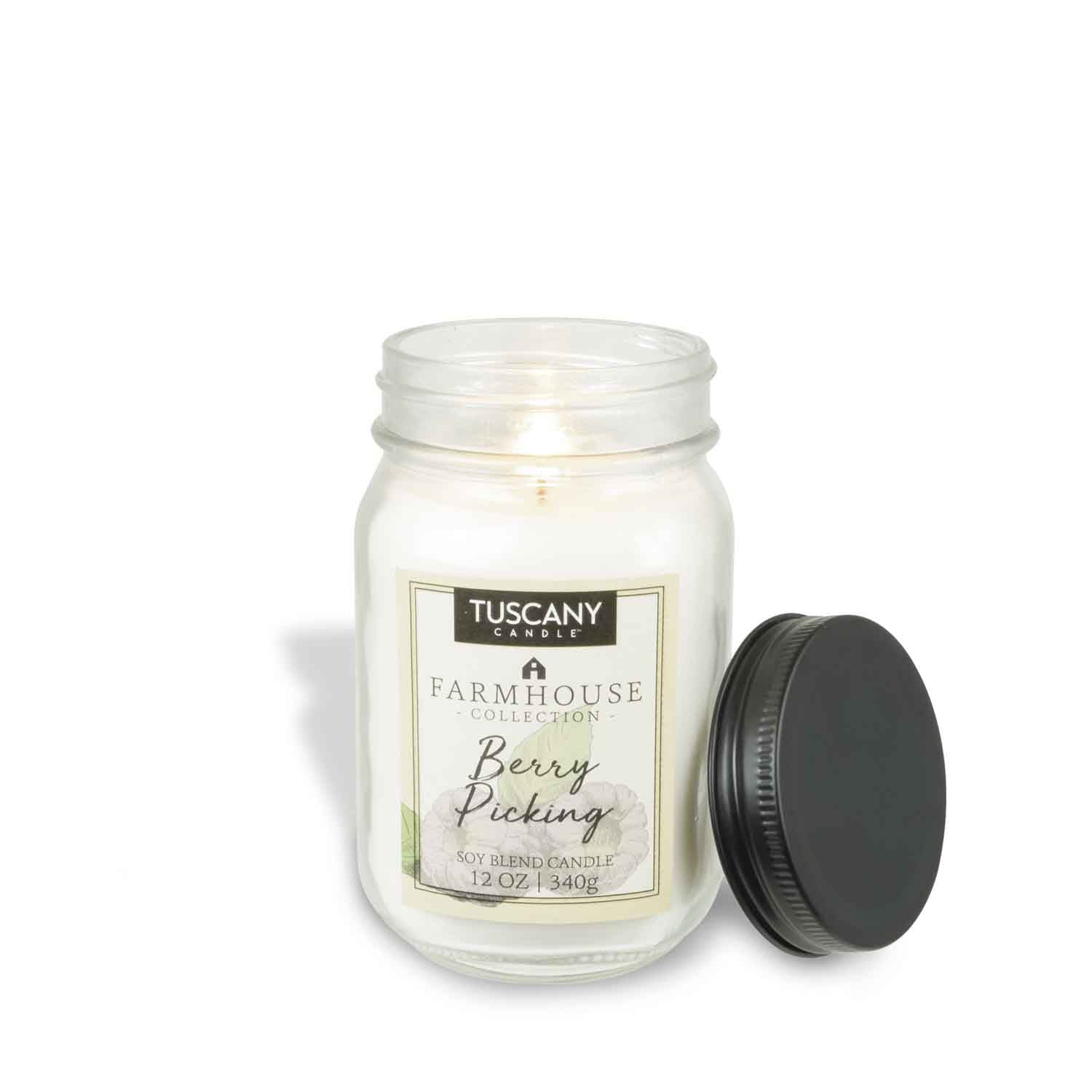 The lit Tuscany Candle® EVD "Berry Picking" from the Farmhouse Collection (12 oz) sits with a black lid beside it, capturing rustic charm.