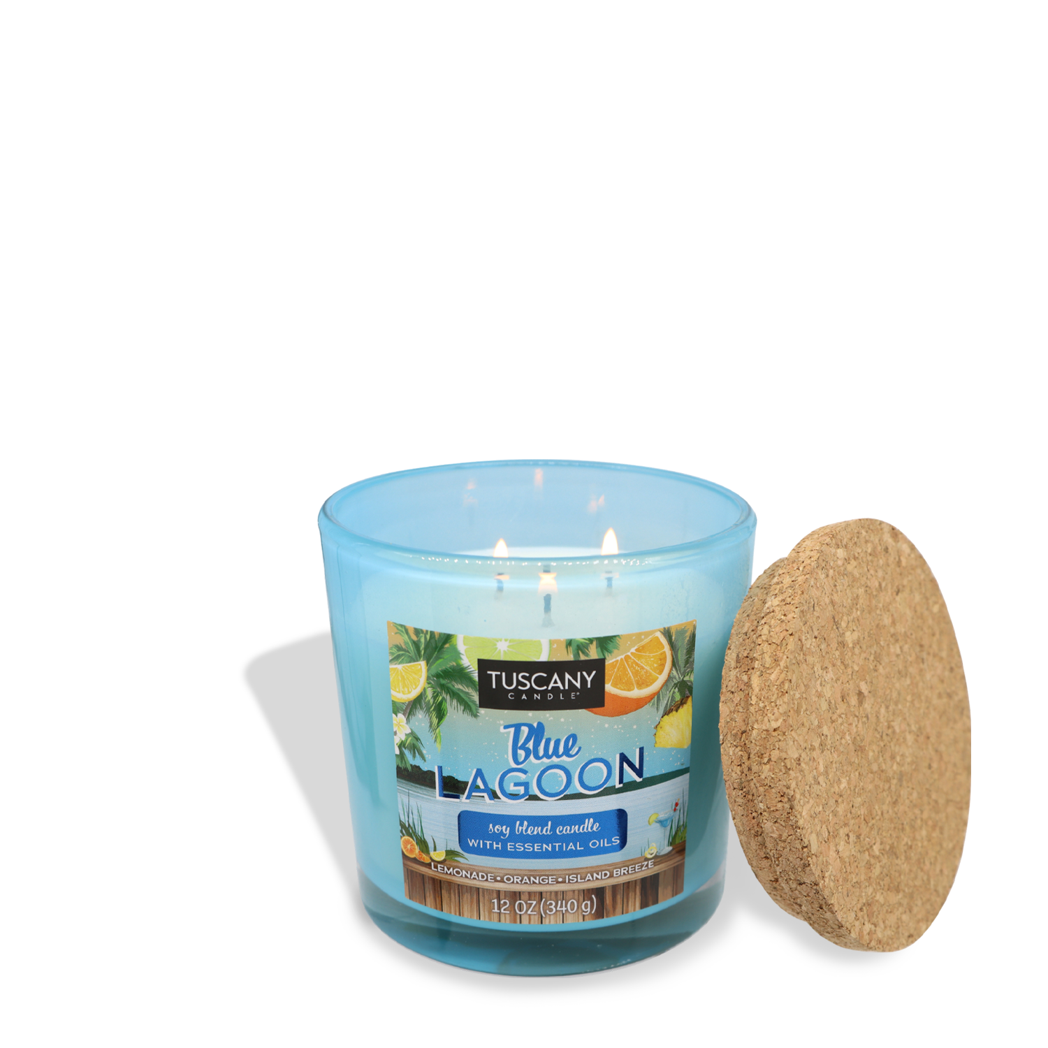 A light blue candle in a glass container labeled "Blue Lagoon (12 oz) – Sunset Beach Bar Collection" by Tuscany Candle® SEASONAL, infused with bright citrus essential oils, placed next to a cork lid. The candle is lit with three visible flames.