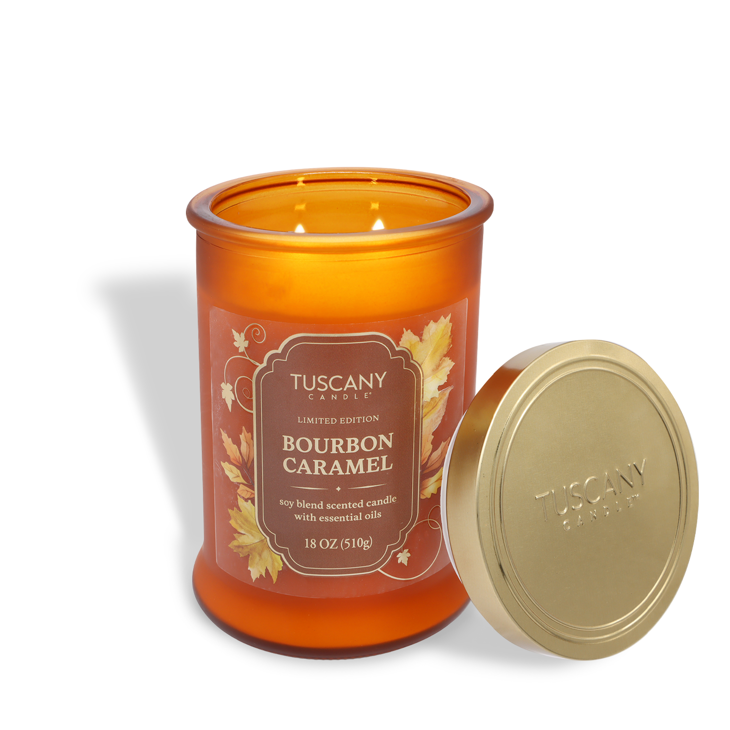 A lit 18 oz Tuscany Candle® SEASONAL "Bourbon Caramel: Cinnamon & Maple Sugar Scented Fall Candle," in an orange glass with a gold lid beside it.