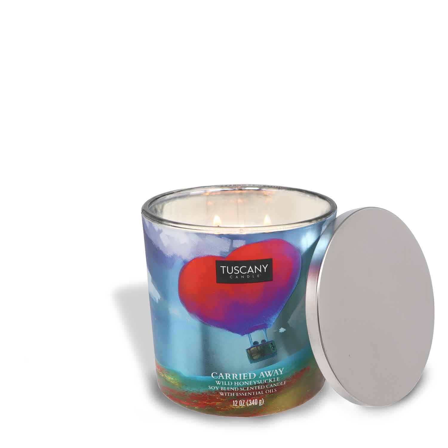 A dreamy Carried Away Scented Jar Candle (12 oz) with a floral Tuscany Candle® SEASONAL lid.