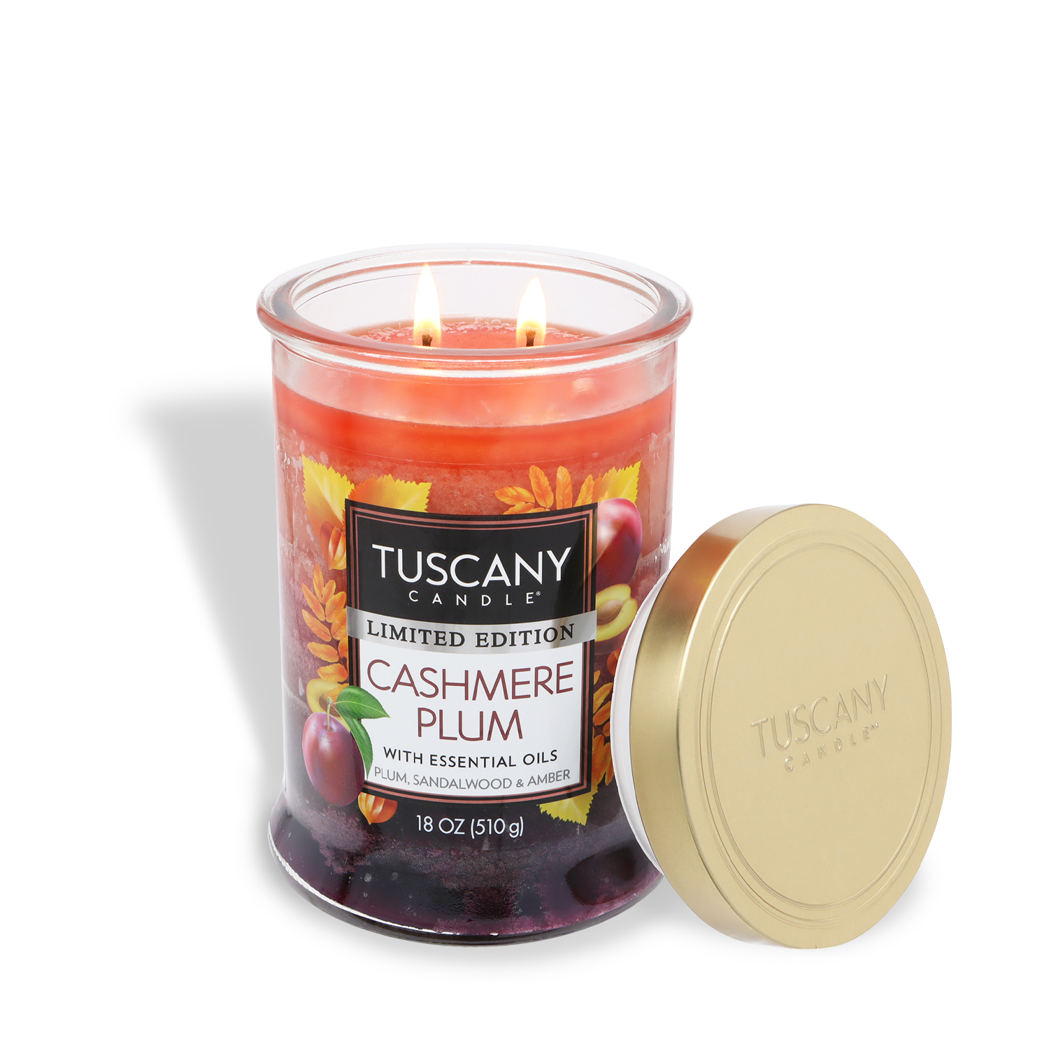 An 18 oz Tuscany Candle® SEASONAL "Cashmere Plum: Sandalwood & Amber Scented Fall Candle" with autumn graphics, two burning wicks, a gold lid beside its glass jar.