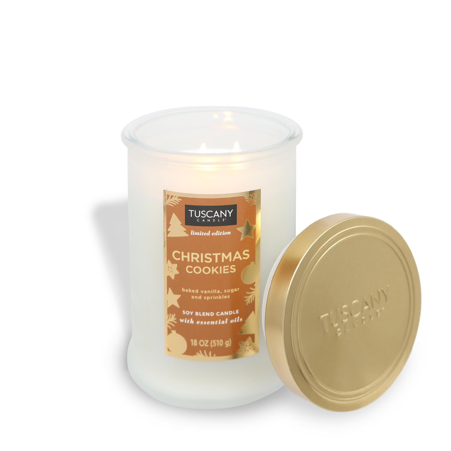 Lit candle labeled "Tuscany Candle® SEASONAL, Christmas Cookies Scented Jar Candle (18 oz) — Winter Reverie Collection," with a white jar and gold lid beside it.