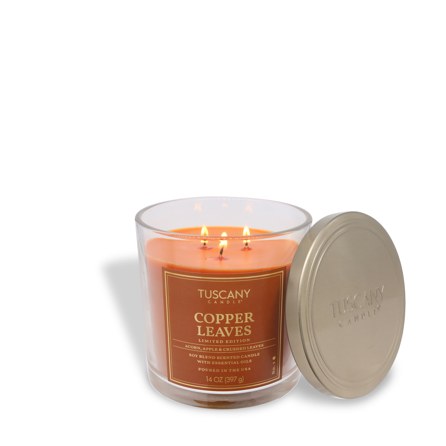 A Tuscany Candle® SEASONAL Copper Leaves: Crisp Apple & Crushed Leaves scented fall candle (14 oz) with three lit wicks in a glass jar, shown beside its metallic lid.