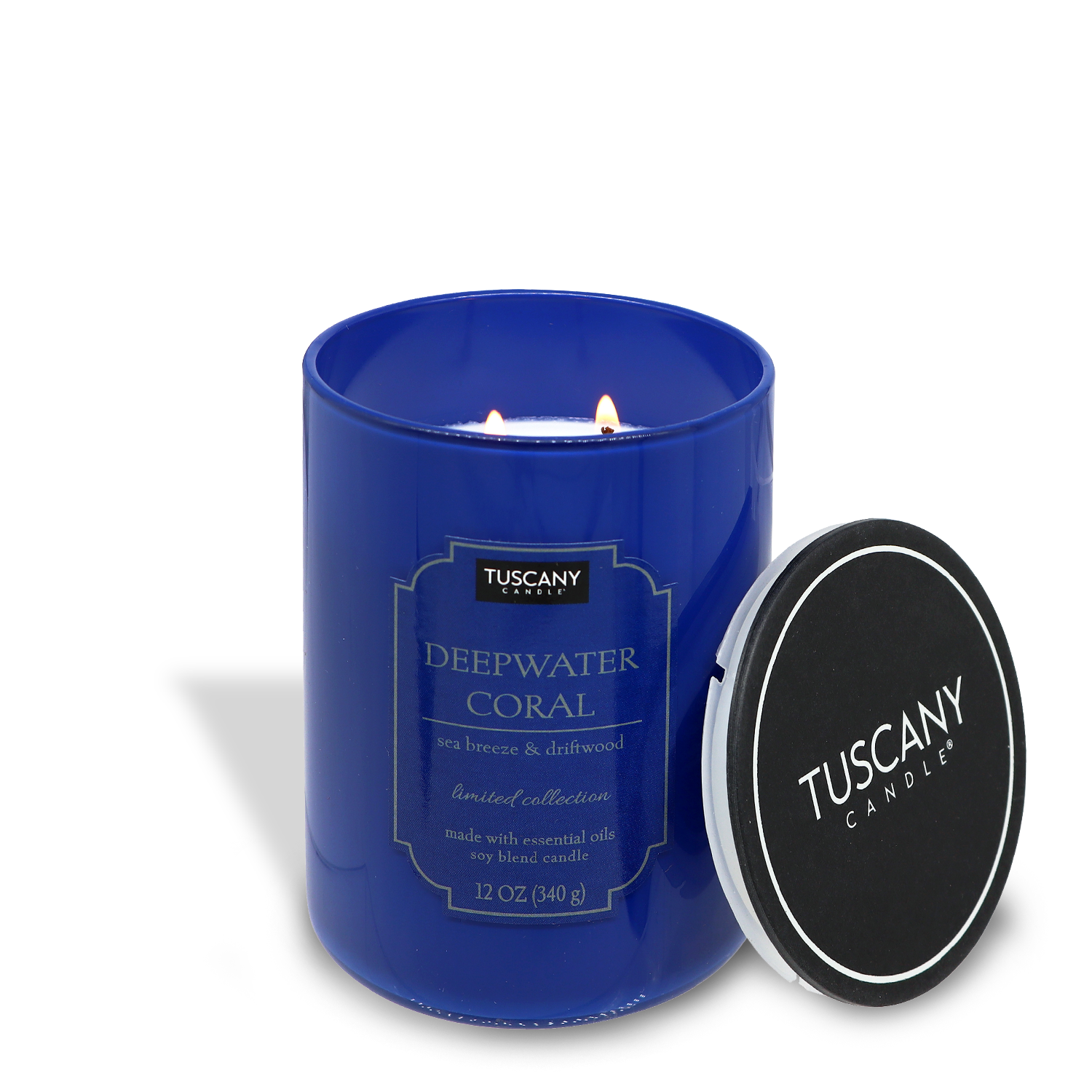 Blue candle labeled "Deepwater Coral (12 oz) – Colorsplash Collection" by Tuscany Candle® EVD, lit, with its black lid off to the side, against a white background.