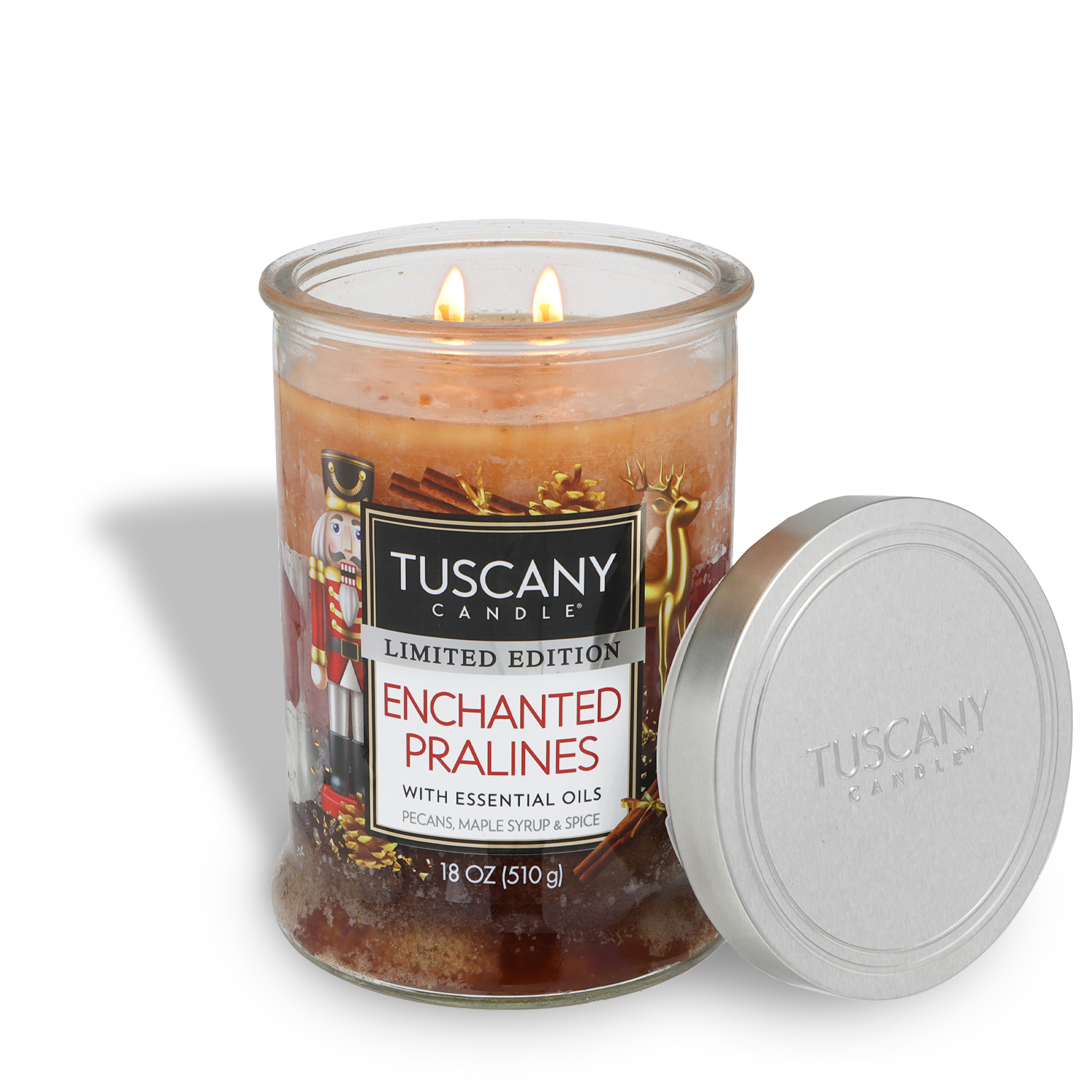 An 18 oz glass jar of Tuscany Candle® SEASONAL Enchanted Pralines: Maple Syrup & Spice Scented Holiday Candle, with two lit wicks and its metal lid resting beside it.