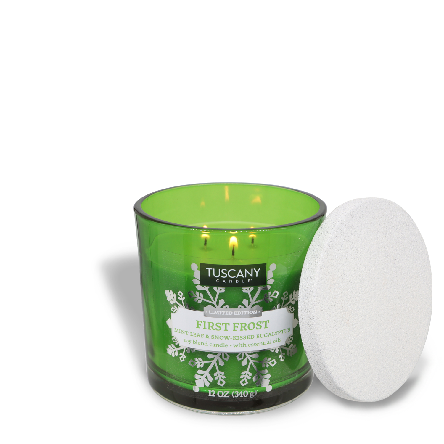 A lit "First Frost" Scented Jar Candle (12 oz) by Tuscany Candle® SEASONAL, featuring a green hue and a delightful blend of mint leaf and snow-kissed eucalyptus, with its white lid resting on the side.