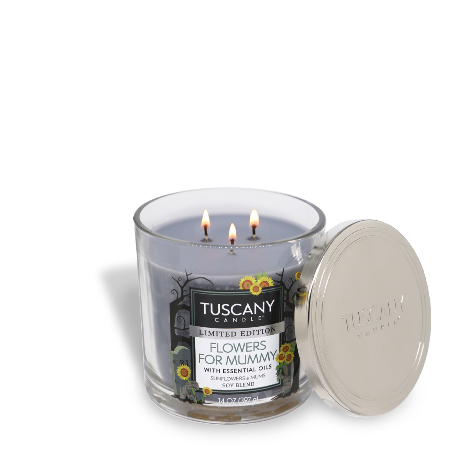 A lit Tuscany Candle® SEASONAL Flowers For Mummy Long-Lasting Scented Jar Candle (14 oz) with essential oils, sunflowers, and mums scent. The premium satin wax candle features three wicks and is housed in a glass jar with a metal lid placed beside it.