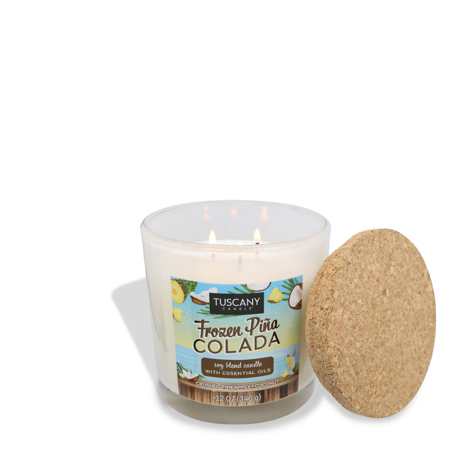 A lit candle in a clear glass jar labeled "Tuscany Candle® SEASONAL Frozen Pina Colada (12 oz) – Sunset Beach Bar Collection." The jar is next to a cork lid with tropical graphics, evoking the scent of soft coconut and crushed pineapple that transports you to a tropical paradise.