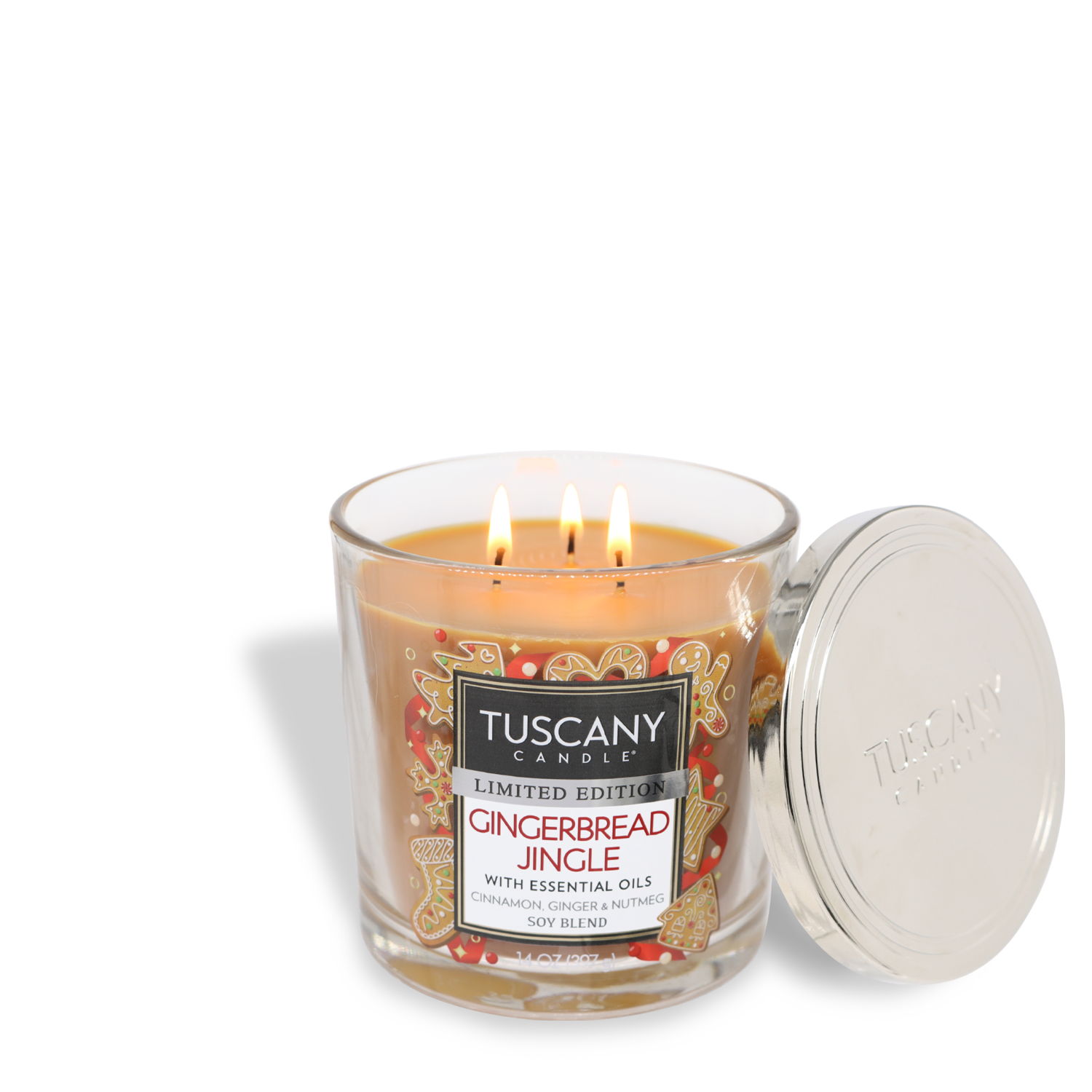 A flickering Gingerbread Jingle Long-Lasting Scented Jar Candle (14 oz) with three wicks, adorned with a metallic lid set beside it, and labeled "Limited Edition Gingerbread Jingle with essential oils" and "Soy Blend," by Tuscany Candle® SEASONAL.