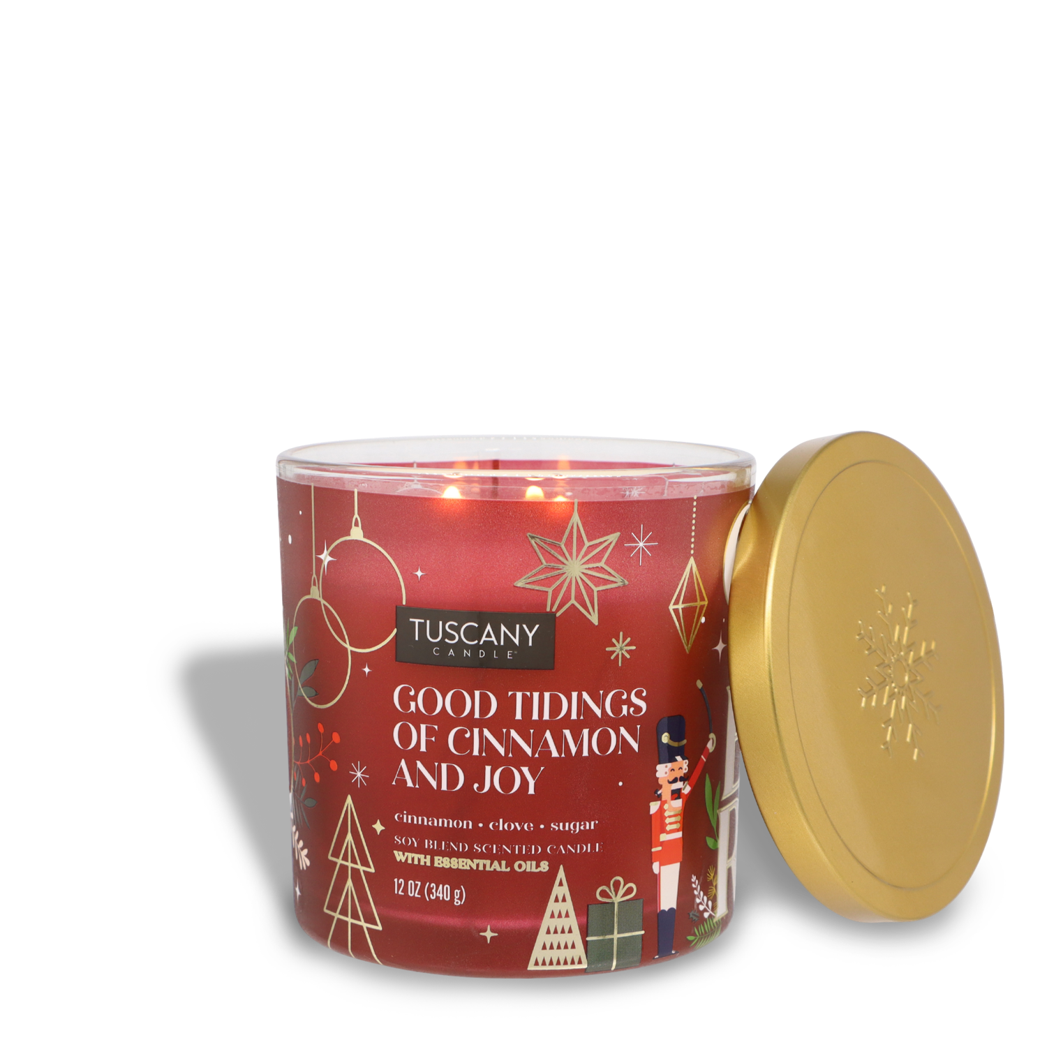 A 12 oz red jar candle with a gold lid, named "Good Tidings of Cinnamon & Joy," is created by Tuscany Candle® SEASONAL. It boasts holiday-themed designs and three wicks.