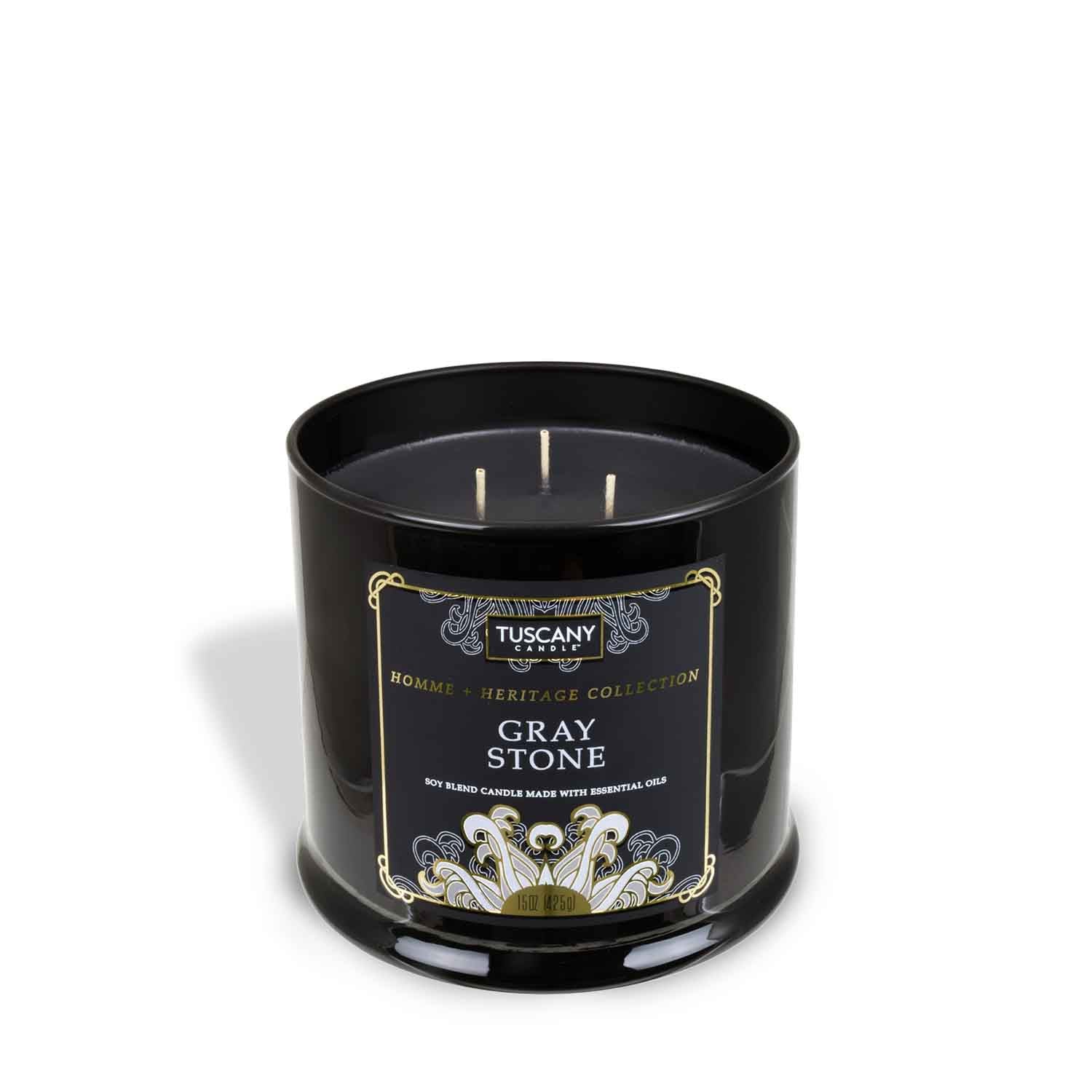 A Gray Stone Scented Jar Candle (15 oz) from the Homme + Heritage collection, crafted with essential oils, showcased in a sleek black tin contrasting against a pristine white background, by Tuscany Candle.