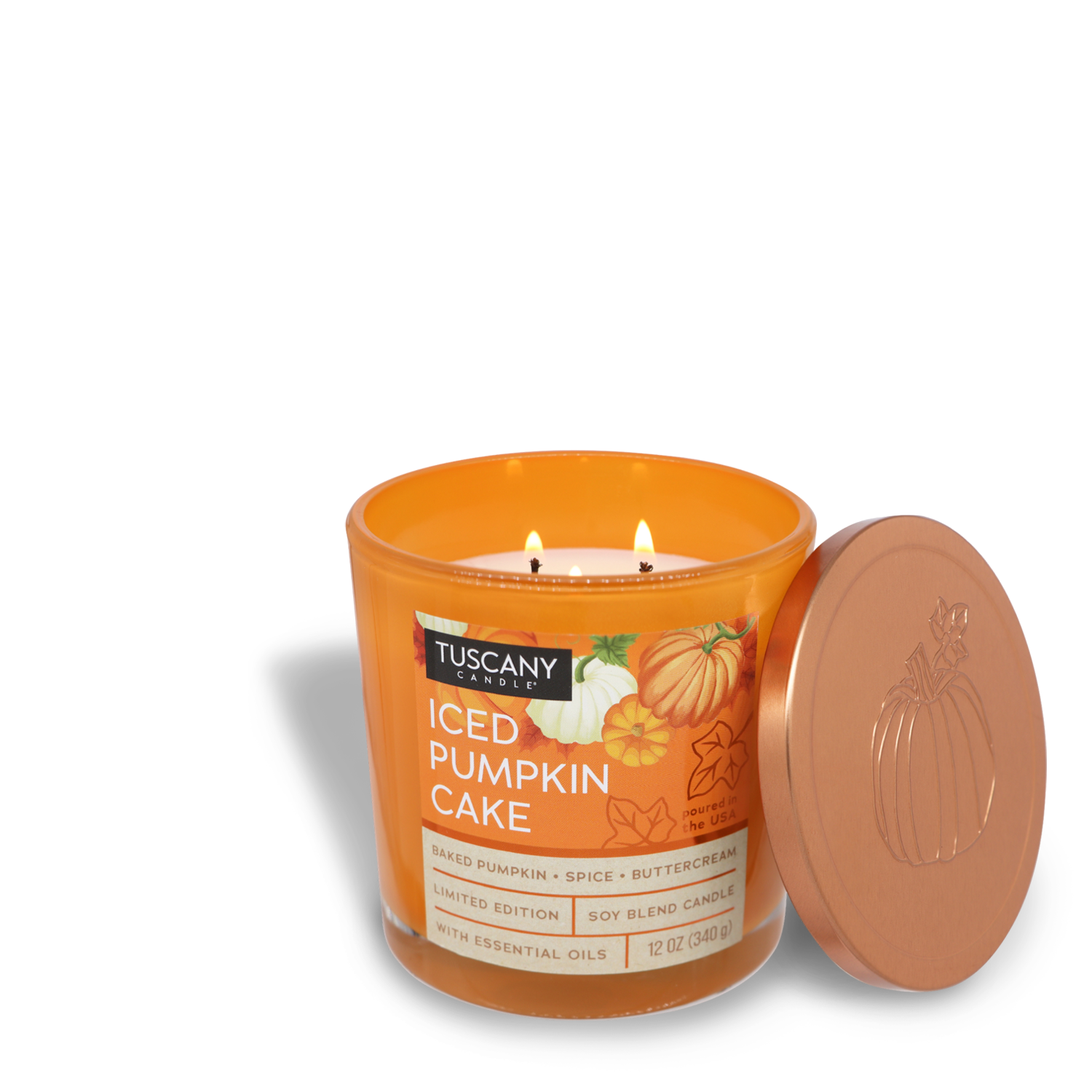 An orange Tuscany Candle® SEASONAL jar candle from the Copper Harvest Collection, labeled "Iced Pumpkin Cake Long-Lasting Scented Jar Candle (12 oz)," with the lid beside it. This limited-edition candle features two lit wicks and is a soy blend with essential oils, perfect for filling your home with an autumn fragrance.