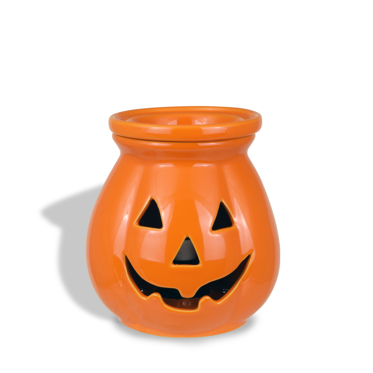 Orange ceramic Jack O' Lantern Wax Melt Warmer with a carved face featuring triangular eyes and mouth, casting a shadow on a white background. Perfect for pairing with Tuscany Candle® SEASONAL wax melts to create an inviting autumn ambiance.