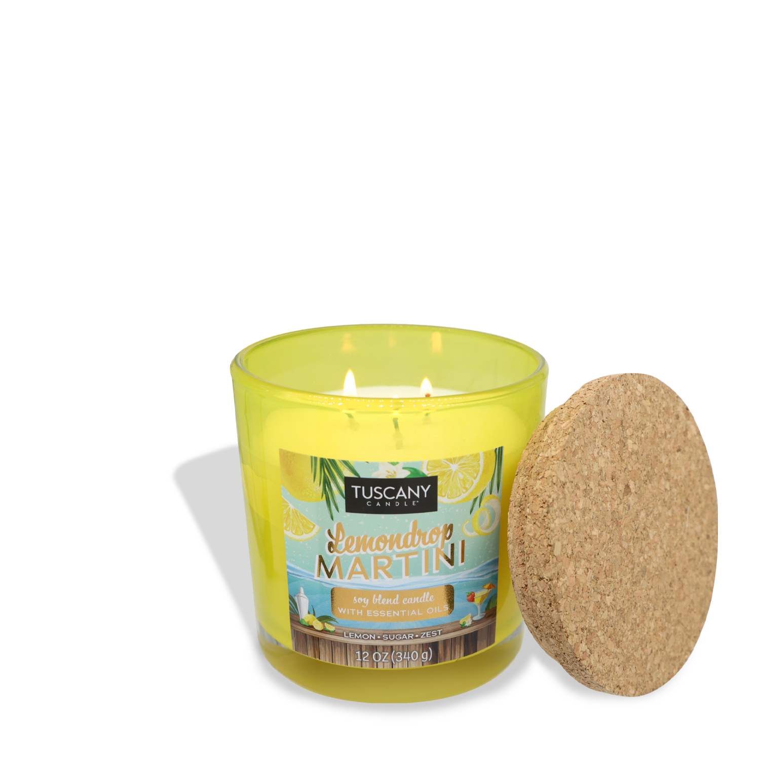 A yellow candle in a glass container labeled "Lemondrop Martini (12 oz) – Sunset Beach Bar Collection" by Tuscany Candle® SEASONAL, with a cork lid placed beside it, evokes the refreshing aroma of lemon zest and sugar.