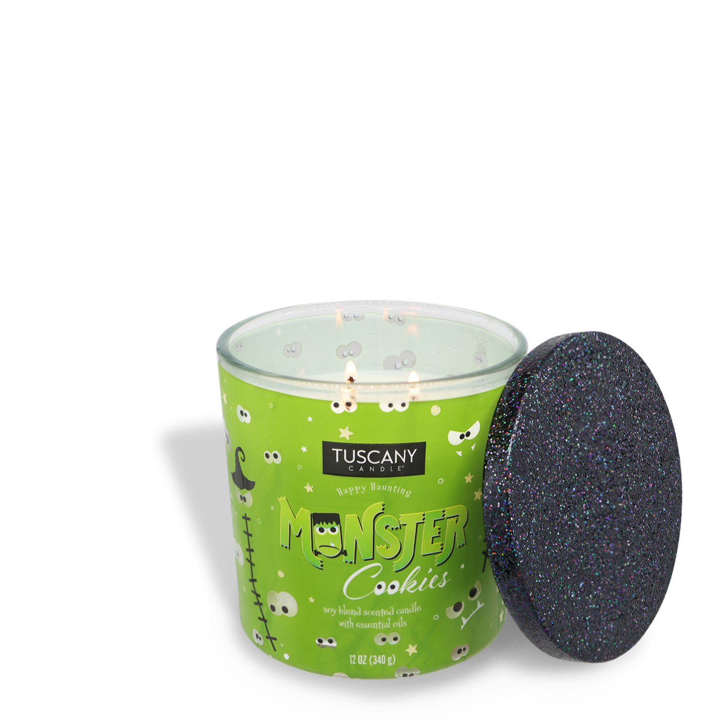 A green Tuscany Candle® SEASONAL labeled "Monster Cookies Long-Lasting Scented Jar Candle (12 oz)" with a black, glitter-covered lid. This scented jar candle features cartoon monster graphics and boasts a soy blend with essential oils, offering delightful fragrance notes throughout.