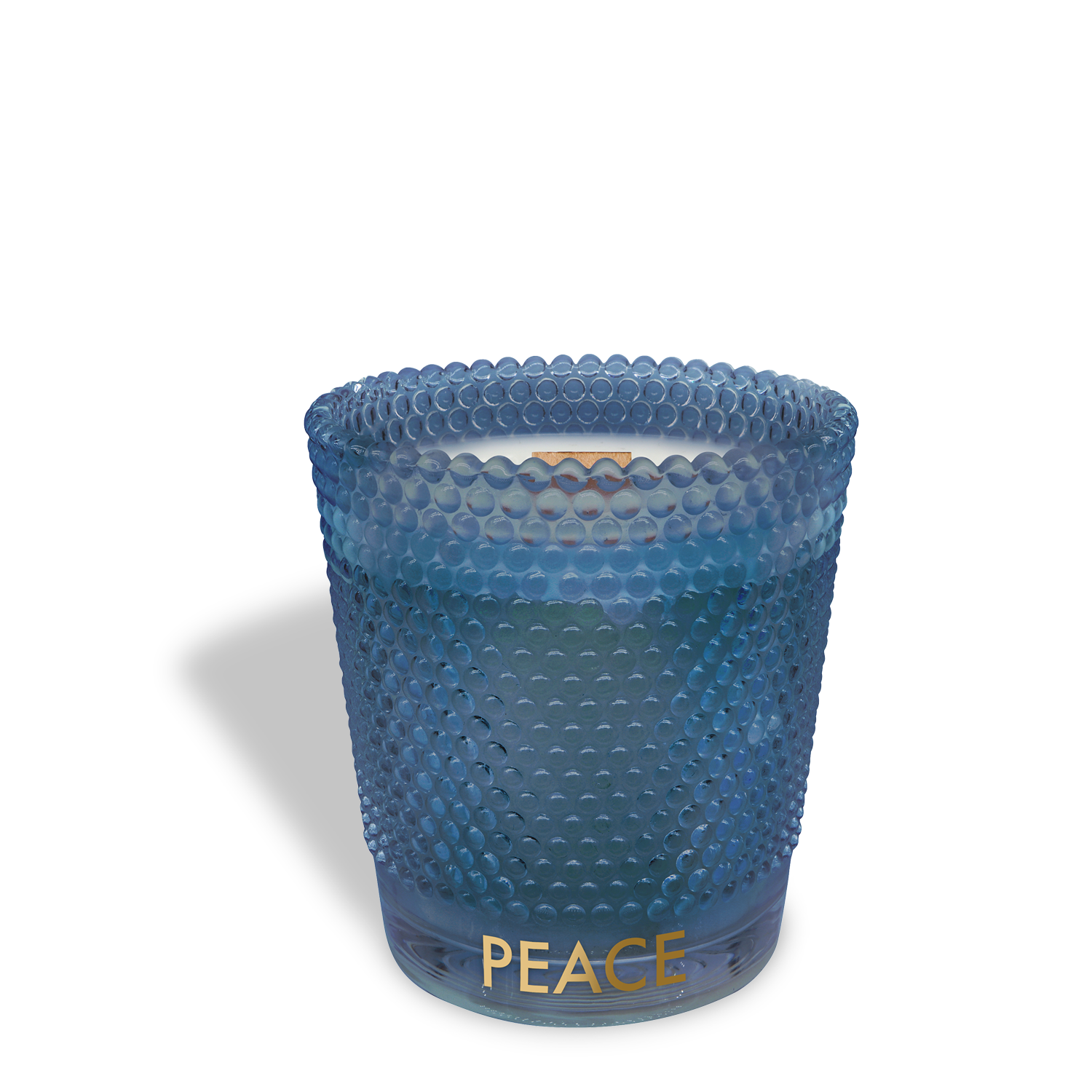 The Tuscany Candle® SEASONAL "Peace" candle features a blue textured glass holder with "PEACE" in gold, a white wooden wick candle, and a warm vanilla & cardamom scent (13 oz)—perfect for the holidays.