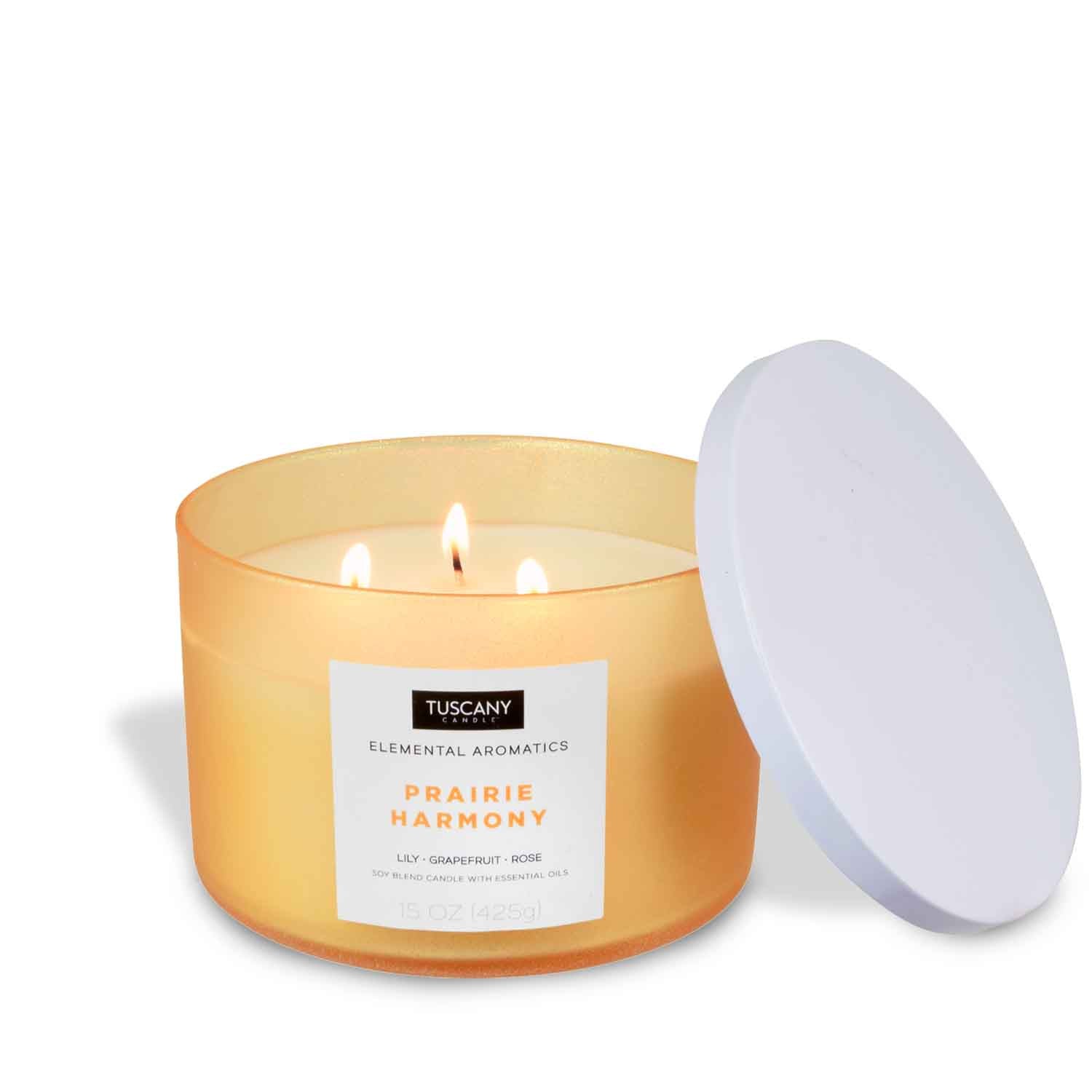 A Prairie Harmony scented candle with an orange lid on it. Brand name: Tuscany Candle® EVD