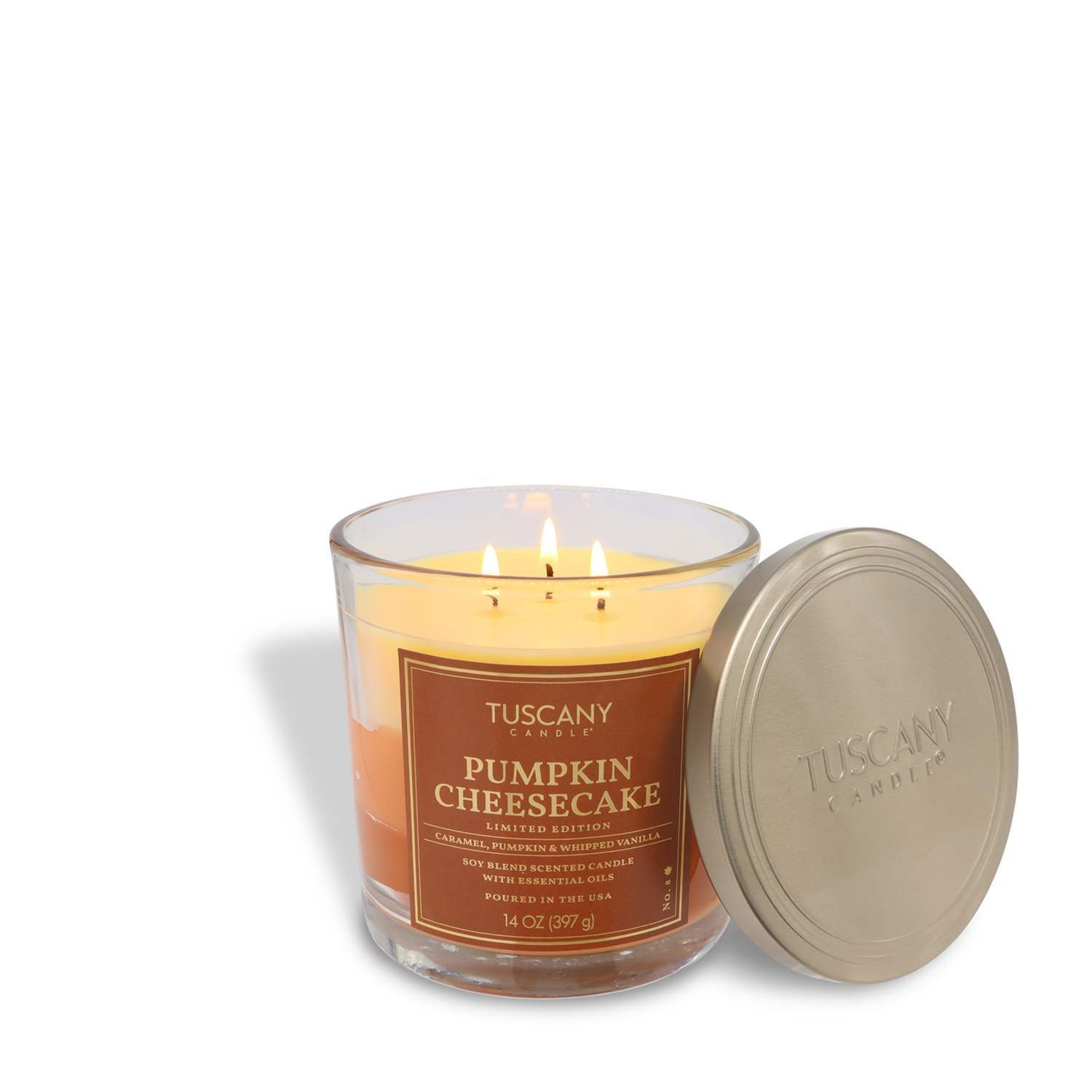 The Tuscany Candle® SEASONAL Pumpkin Cheesecake: Vanilla & Roasted Cinnamon Scented Fall Candle (14 oz) is in a clear glass jar with three wicks, shown with its silver lid placed beside it.