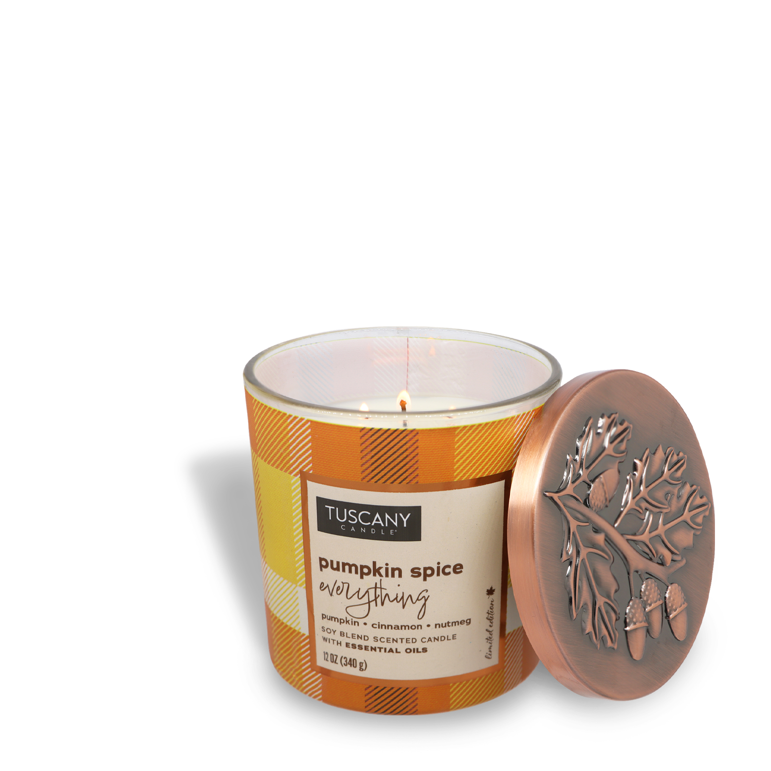 A lit Tuscany Candle® SEASONAL Pumpkin Spice Everything Long-Lasting Scented Jar Candle (12 oz) from the Autumn Flannels Collection, next to a decorative lid featuring embossed leaves and acorns.