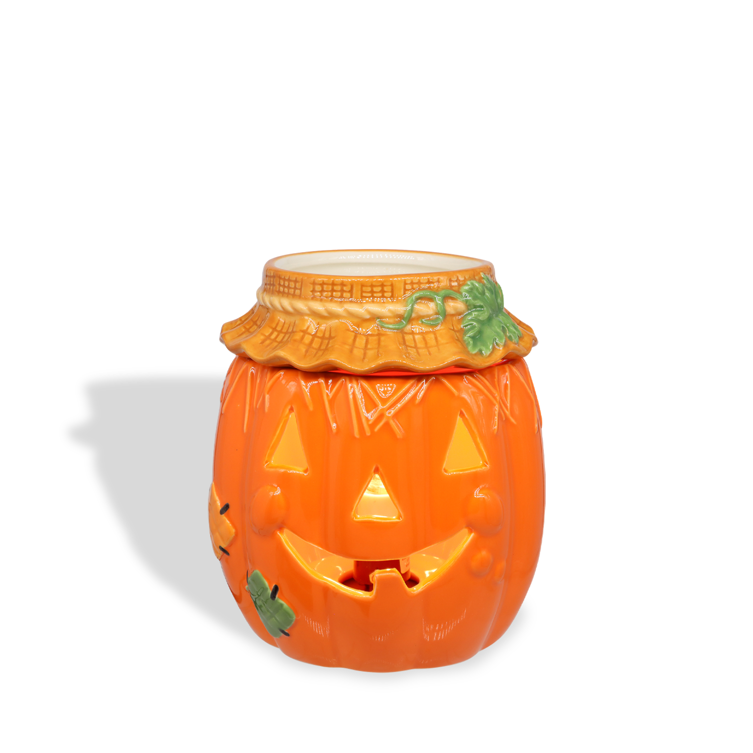 The Tuscany Candle® SEASONAL Pumpkin Wax Melt Warmer features carved eyes, nose, and mouth with green leaves and a textured rim—ideal as jack-o’-lantern décor or a wax melt warmer for your seasonal display. Shown on a white background.