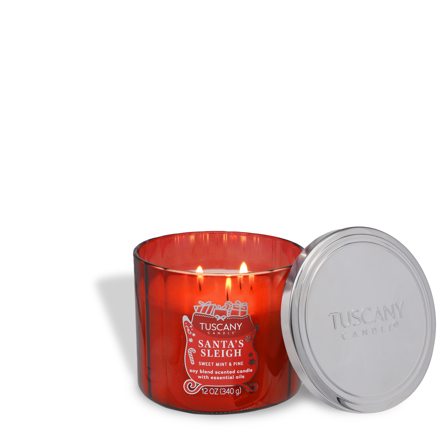 A red Tuscany Candle® SEASONAL "Santa's Sleigh: Sweet Mint & Pine" 12 oz jar from the Winter Icons Collection with two lit wicks and a silver lid beside it.