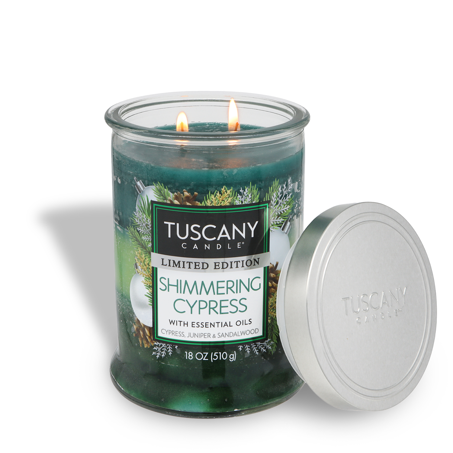 An 18 oz Tuscany Candle® SEASONAL Shimmering Cypress: Juniper & Sandalwood scented holiday candle with two lit wicks and its metal lid resting beside it.