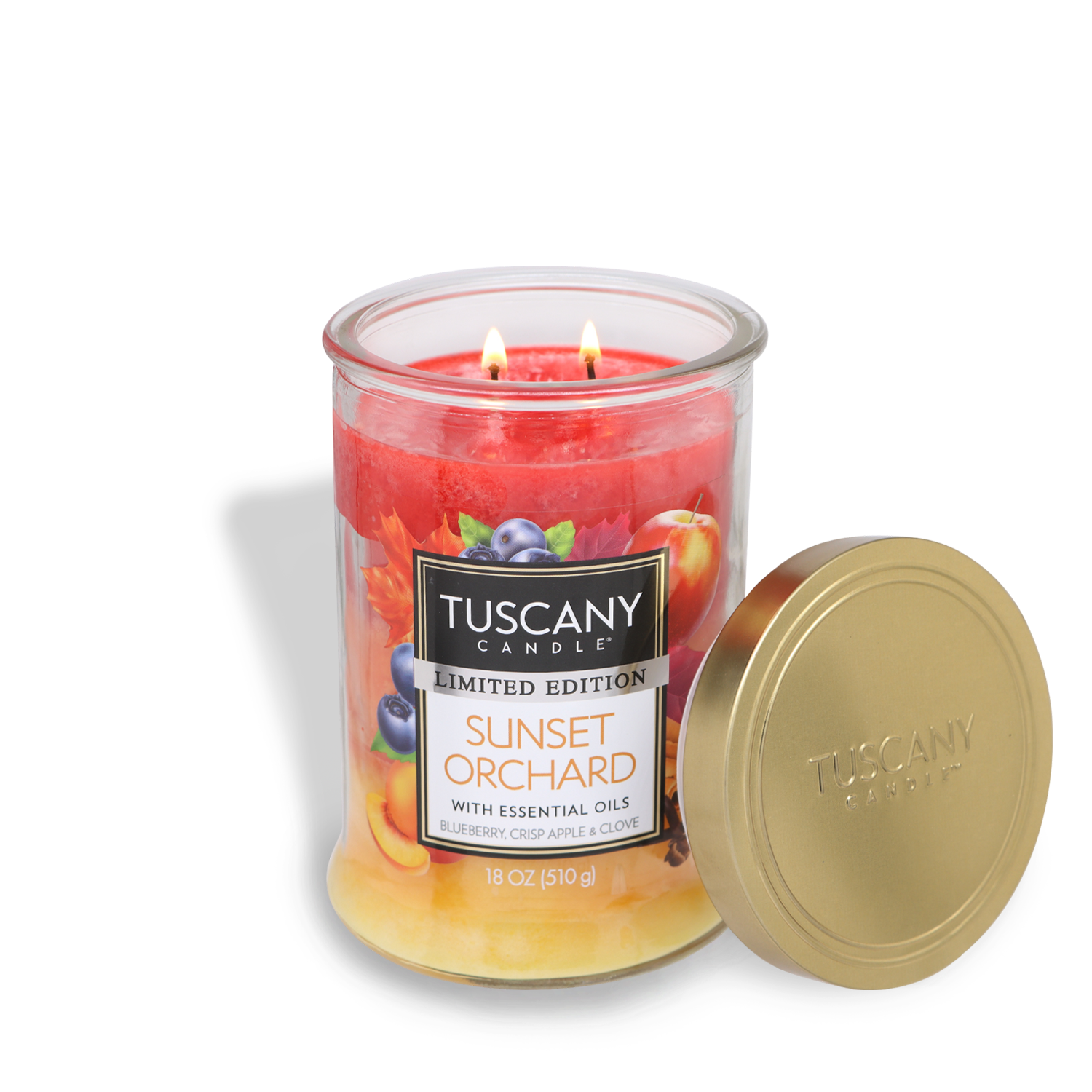 A Tuscany Candle® SEASONAL Sunset Orchard Long-Lasting Scented Jar Candle (18 oz), with two lit wicks. The jar features images of blueberries, apples, and cloves. The lid is placed on the side. Infused with essential oils for a rich aroma. Candle weight is 18 oz (510 g).