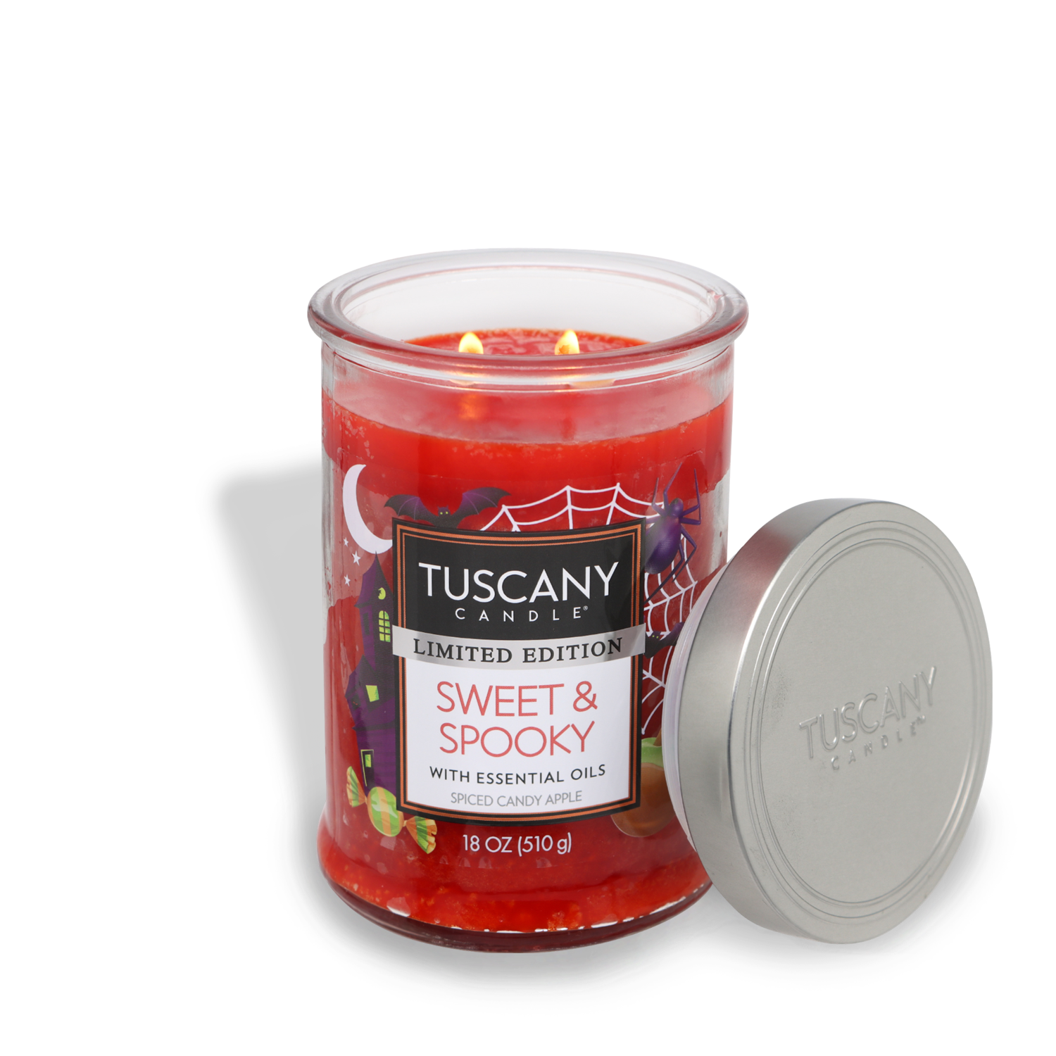 A red Tuscany Candle® SEASONAL labeled "Sweet & Spooky Long-Lasting Scented Jar Candle (18 oz)," scented with spiced candy apple and featuring a lid off to the side, promises an enchanting burn time with its high-quality essential oils.