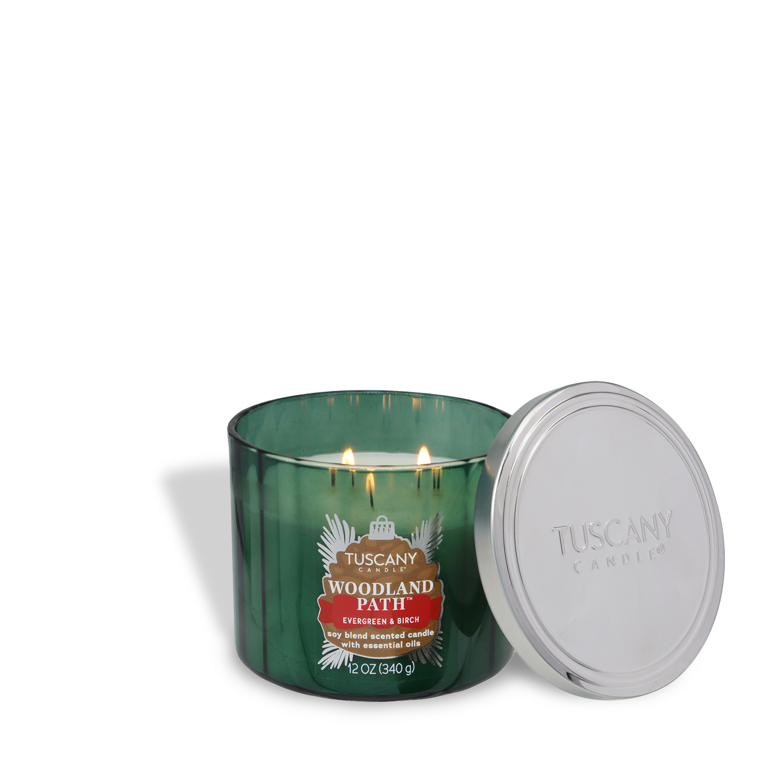 A green Tuscany Candle® SEASONAL jar labeled "Woodland Path: Evergreen & Birch Scented Holiday Candle (12 oz) – Winter Icons Collection" with two lit wicks and a silver lid beside it.
