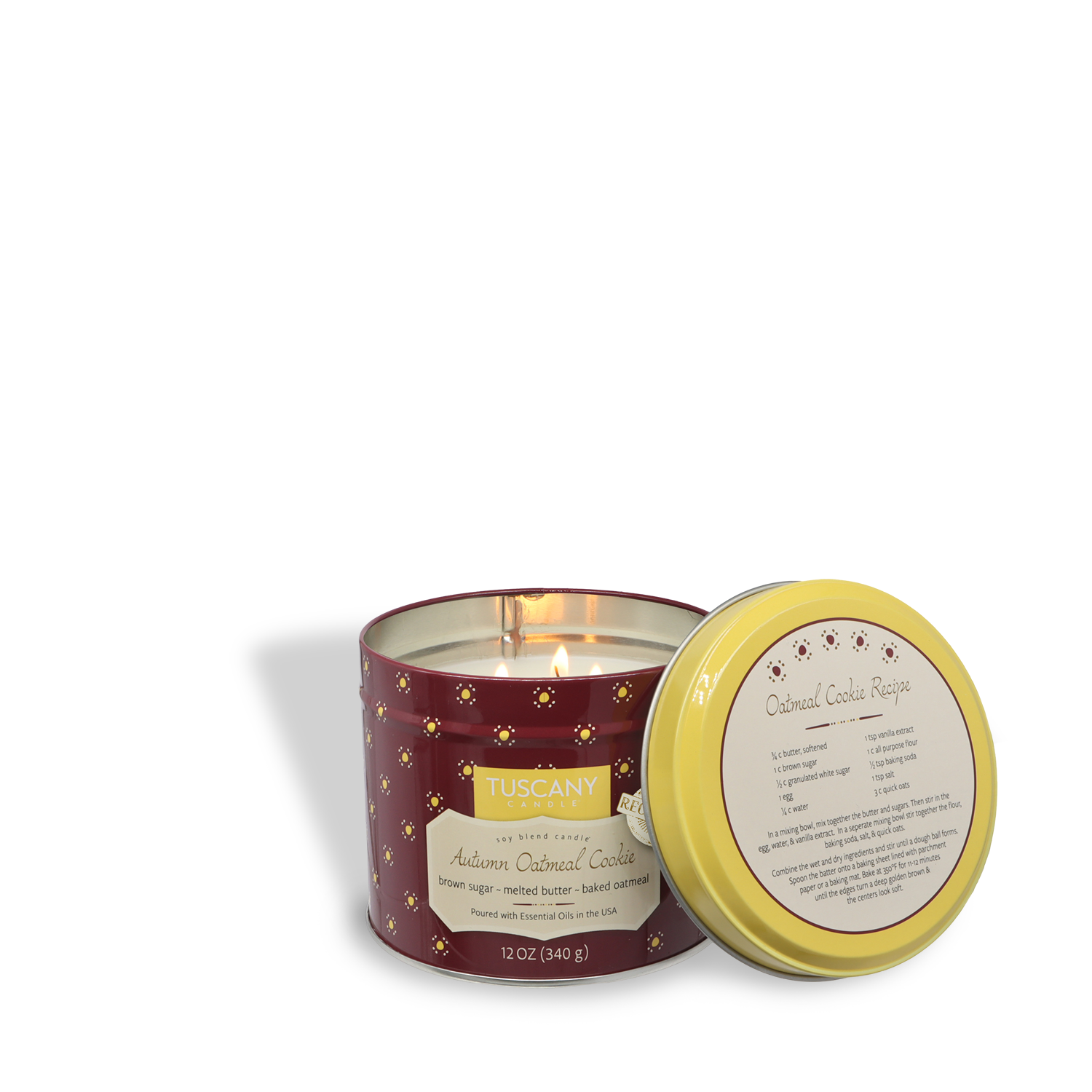 A lit Tuscany Candle® SEASONAL "Autumn Oatmeal Cookie: Harvest Spices Scented Fall Candle" (12 oz, Bakery Tins Collection) in a maroon container with yellow lid sits beside its lid featuring an oatmeal cookie recipe.