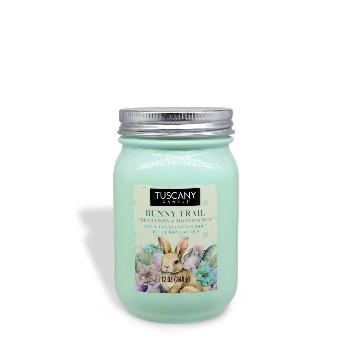 A 12 oz light green Tuscany Candle® SEASONAL jar labeled "Bunny Trail," with a rabbit and floral design, features a linen scent and a metal lid.