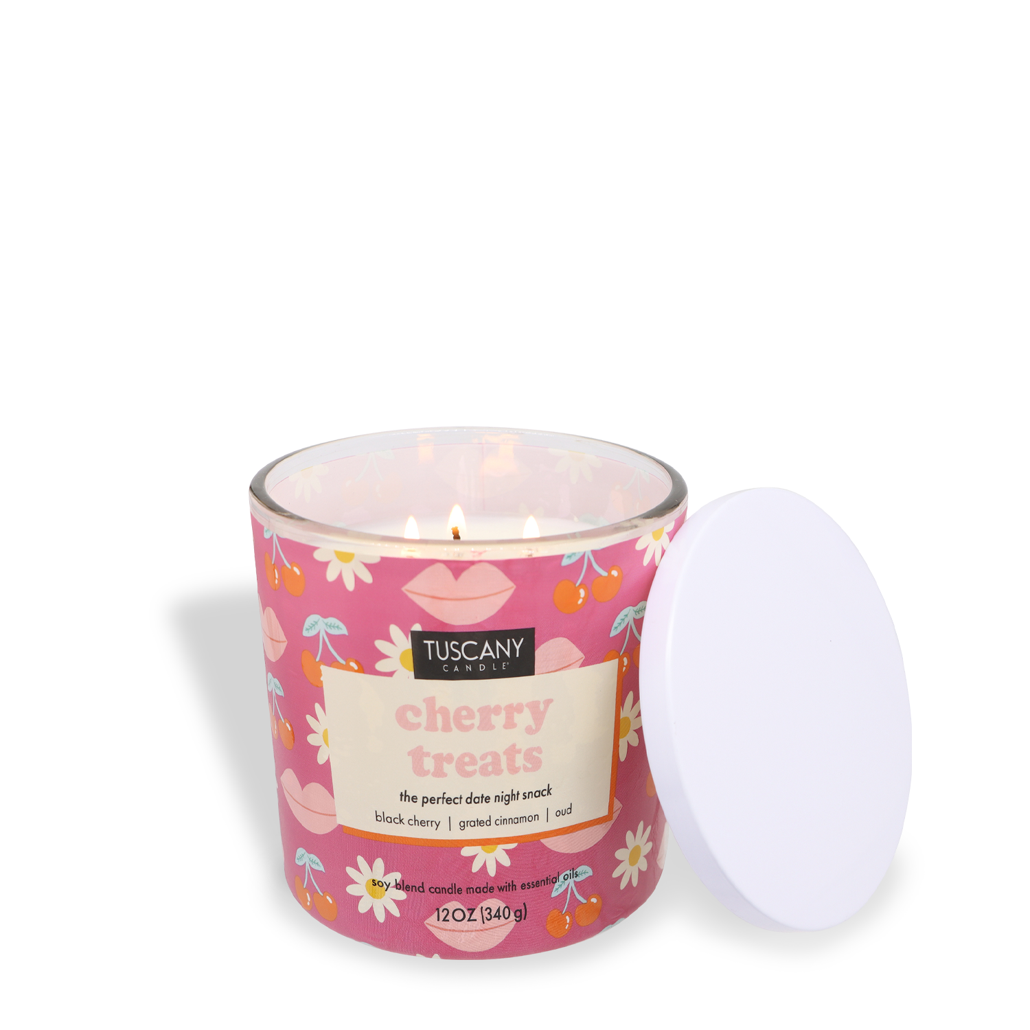 A pink scented jar candle labeled "Cherry Treats: Cinnamon & Cherry Scented Valentine’s Day Candle (12 oz)" by Tuscany Candle® SEASONAL, its wick lit against a white background, fills the air with a delightful cinnamon and cherry fragrance—perfect for setting a romantic mood on Valentine's Day.