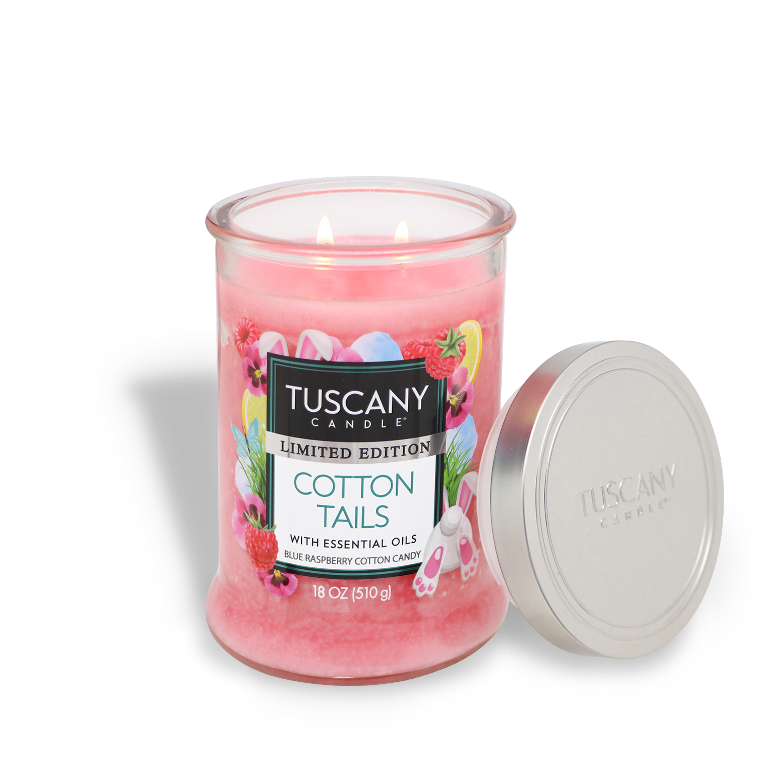 A pink Tuscany Candle® SEASONAL jar labeled "Cotton Tails: Raspberry Scented Easter Candle (18 oz)" with the lid beside it is lit with two wicks.