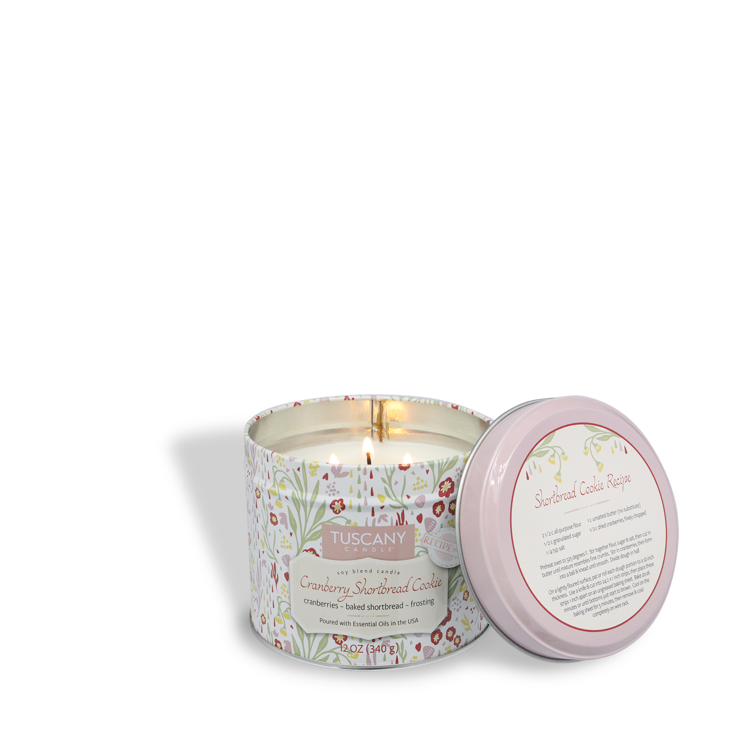A Tuscany Candle® SEASONAL 12 oz “Cranberry Shortbread Cookie: Homemade Frosting” candle from the Bakery Tins Collection sits in a decorative tin, lid to the side showing a printed cookie recipe.
